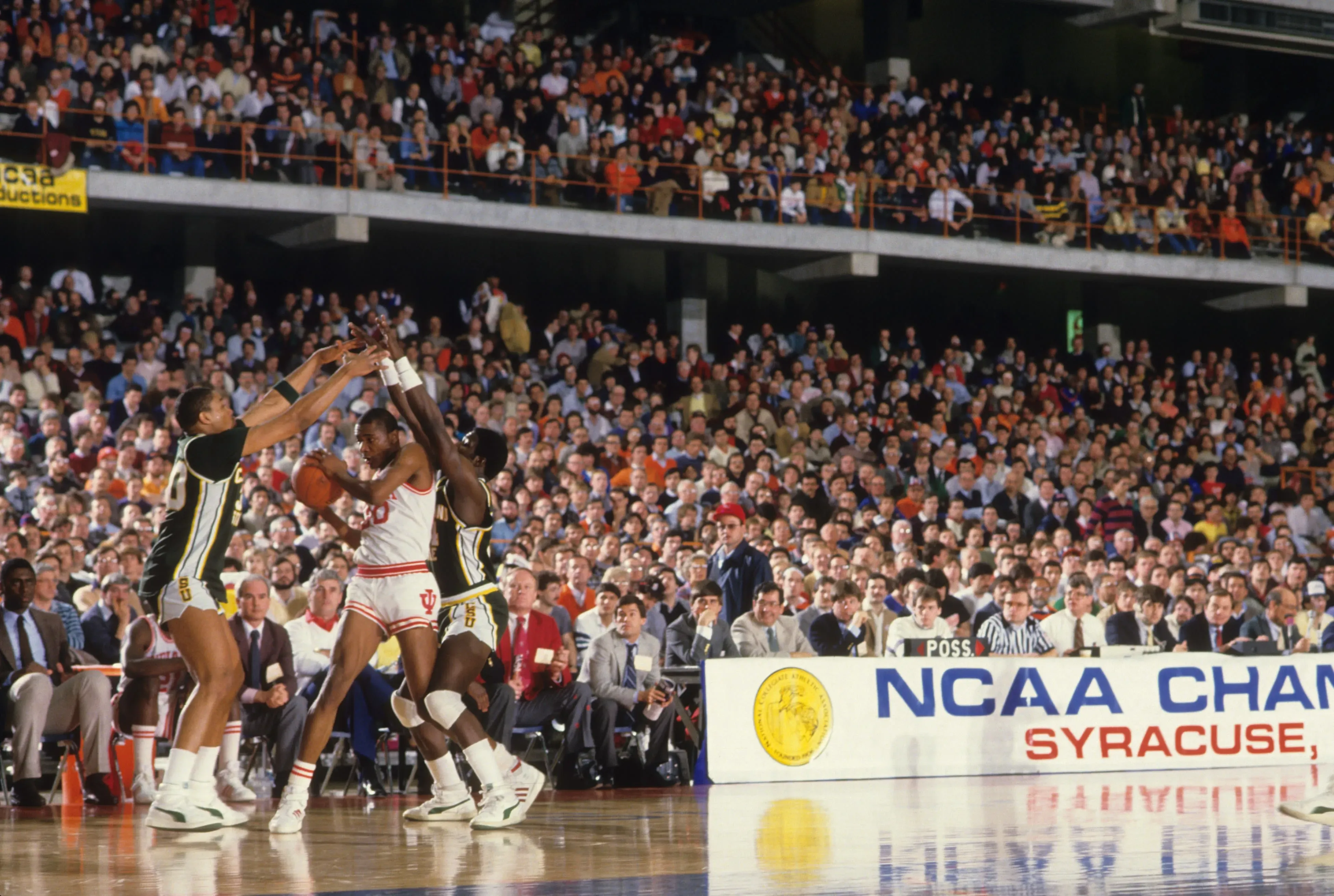 مباراة كرة سلة NCAA في سيراكيوز، حيث يتنافس فريقان في أجواء حماسية أمام جمهور كبير، مع التركيز على لحظة حاسمة في اللعب.