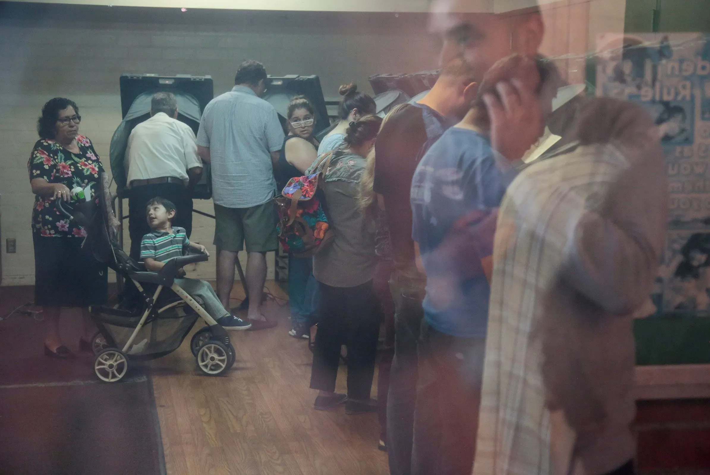 صورة لمجموعة من الأشخاص في مركز اقتراع، حيث ينتظر البعض في طوابير بينما يتفاعل آخرون مع أطفالهم، مما يعكس أهمية المشاركة في الانتخابات.