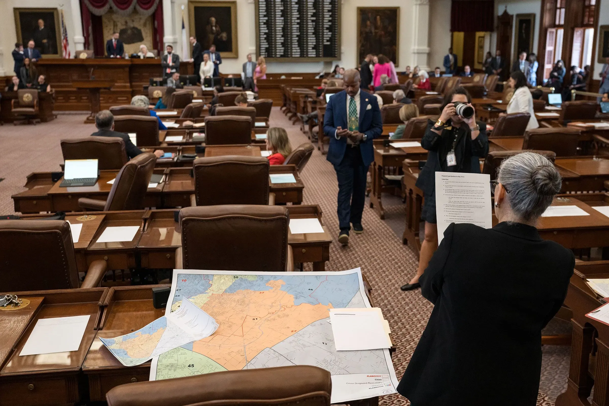 جلسة في مجلس النواب تُظهر خريطة انتخابية على الطاولة، مع أعضاء يتفاعلون في الخلفية، تعكس أهمية الانتخابات المقبلة.