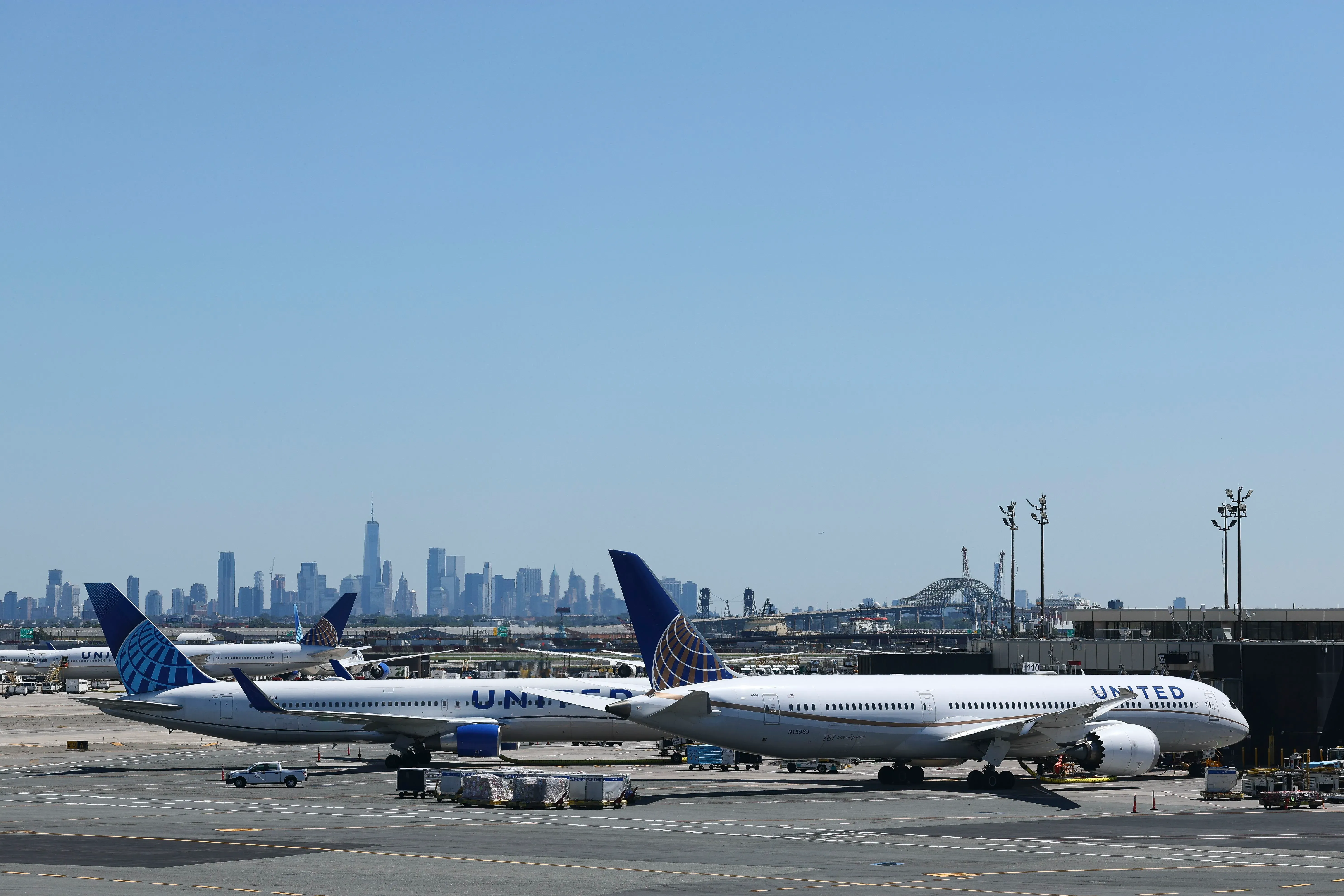 صورة لمطار مع طائرات تابعة لشركة يونايتد في المقدمة، وخلفها skyline لمدينة نيويورك، تعكس تجربة السفر الجوي المتزايدة الرضا.