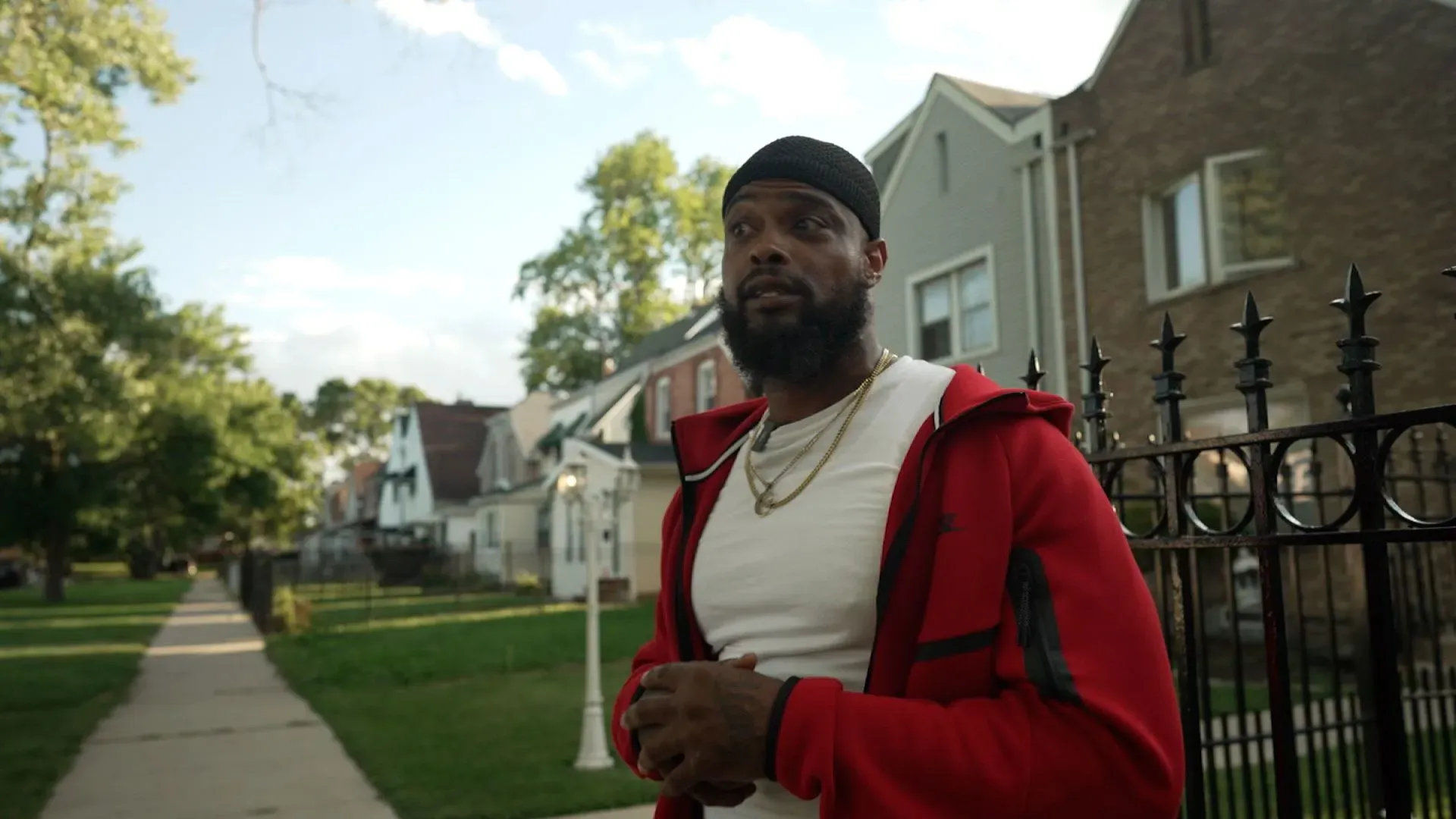 سيدريك هوكينز، وسيط مناهض للعنف المسلح في شيكاغو، يتحدث في حي بولمان، مع خلفية منازل سكنية.