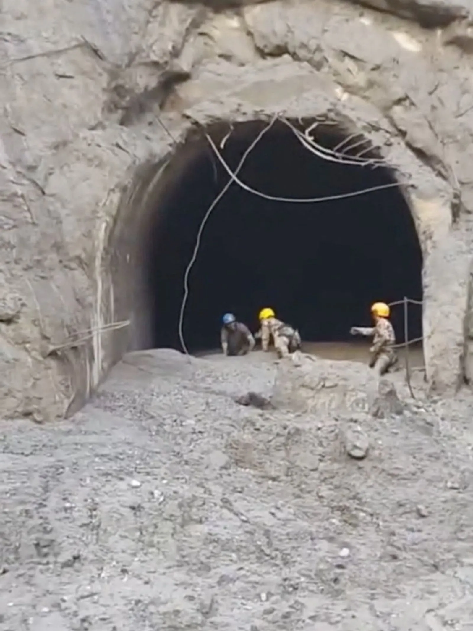 عمال إنقاذ يرتدون خوذاً يقتربون من نفق مغطى بالأتربة في موقع كارثة فيضان نهر Trishuli بجبال الهيمالايا في نيبال.