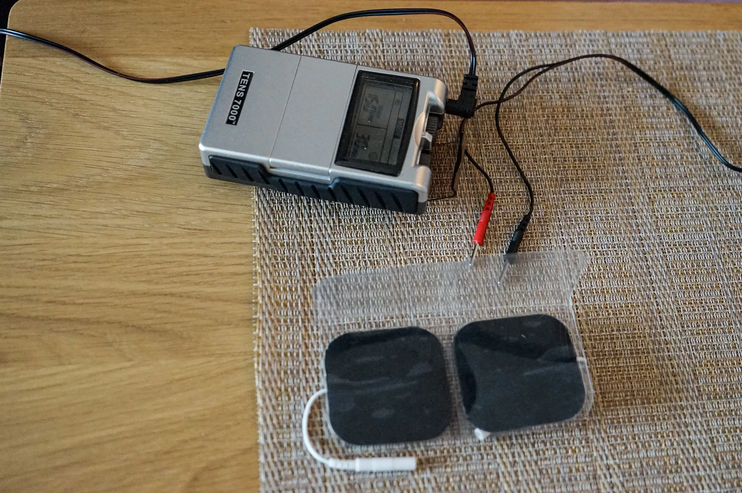 جهاز تحفيز كهربائي للعضلات (TENS) موصول بأسلاك، يستخدم لتخفيف الألم بعد استئصال الثدي، مما يعكس تحديات متلازمة الألم ما بعد الاستئصال.