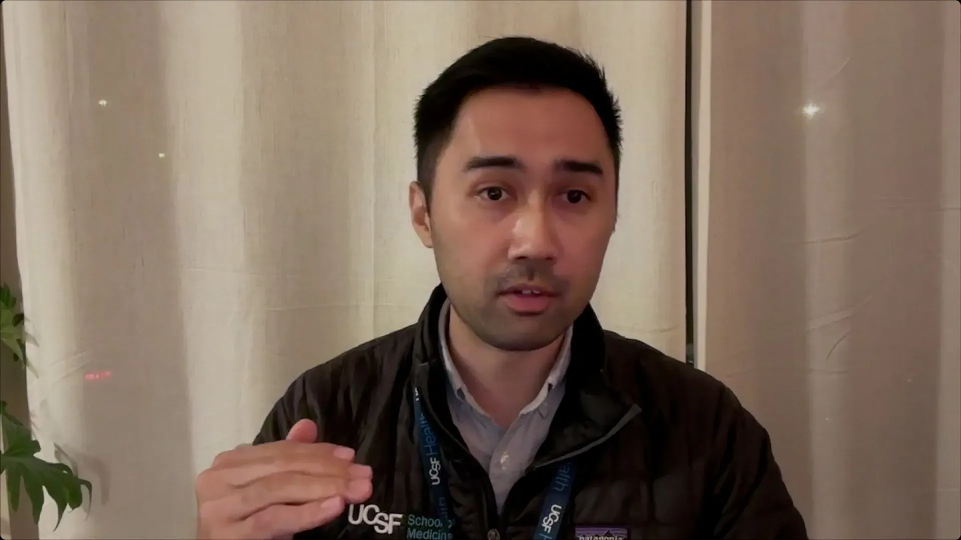 رجل يتحدث بجدية، مرتديًا سترة داكنة، مع خلفية بيضاء، يناقش تأثير الذكاء الاصطناعي على الصحة العقلية.