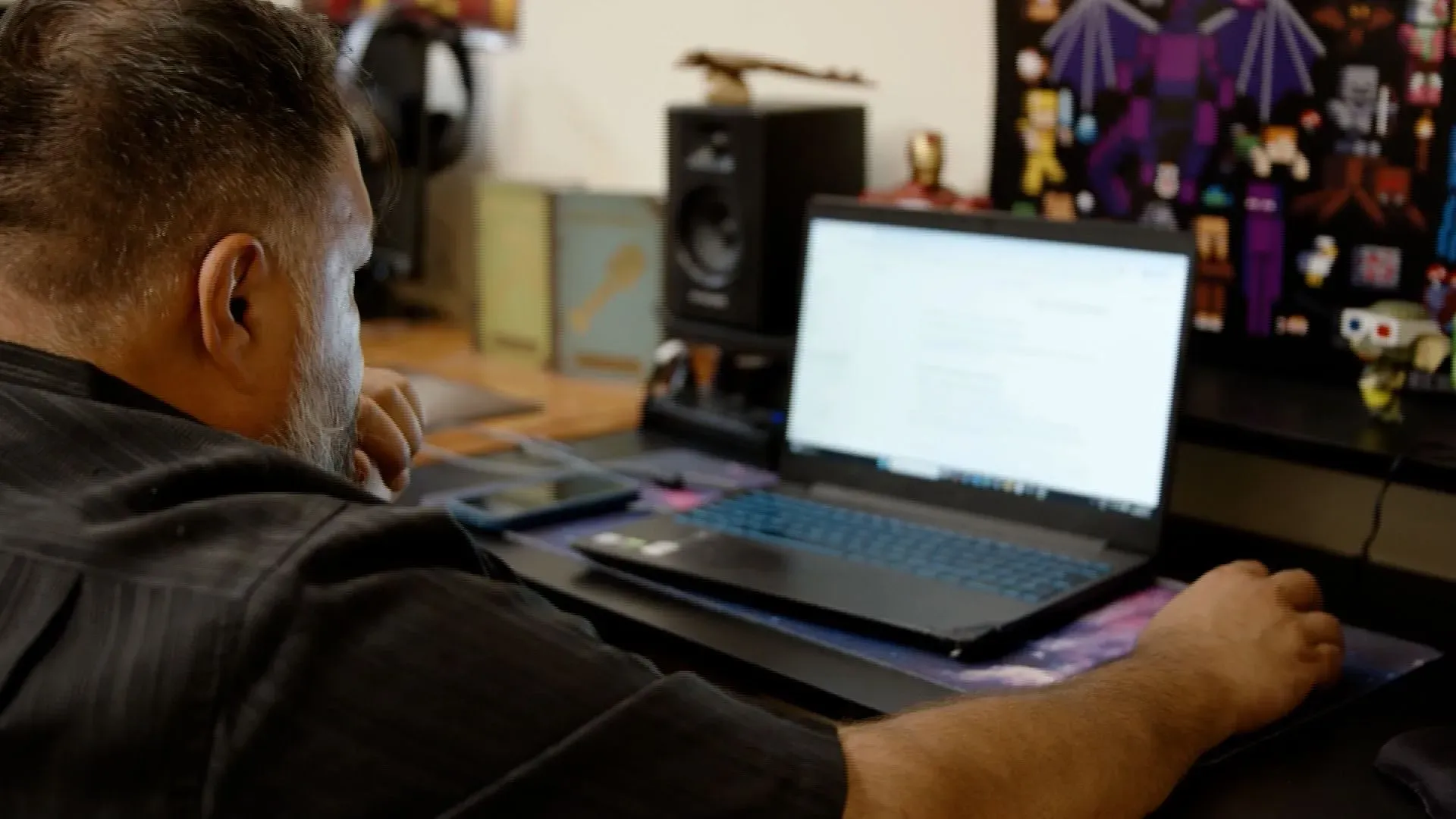 رجل يجلس أمام حاسوبه المحمول في غرفة مليئة بالأدوات التكنولوجية، مشغولاً في محادثة مع ChatGPT حول الذكاء الاصطناعي.