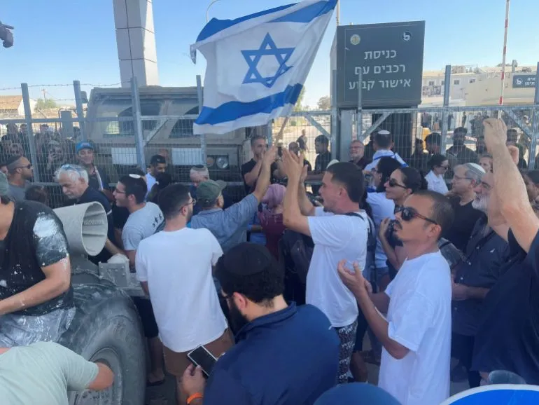 تجمع حشود من المتظاهرين في موقع معبر إسرائيلي، يحملون الأعلام ويرفعون شعارات، تعبيرًا عن دعمهم أو احتجاجهم في سياق الأحداث الجارية.