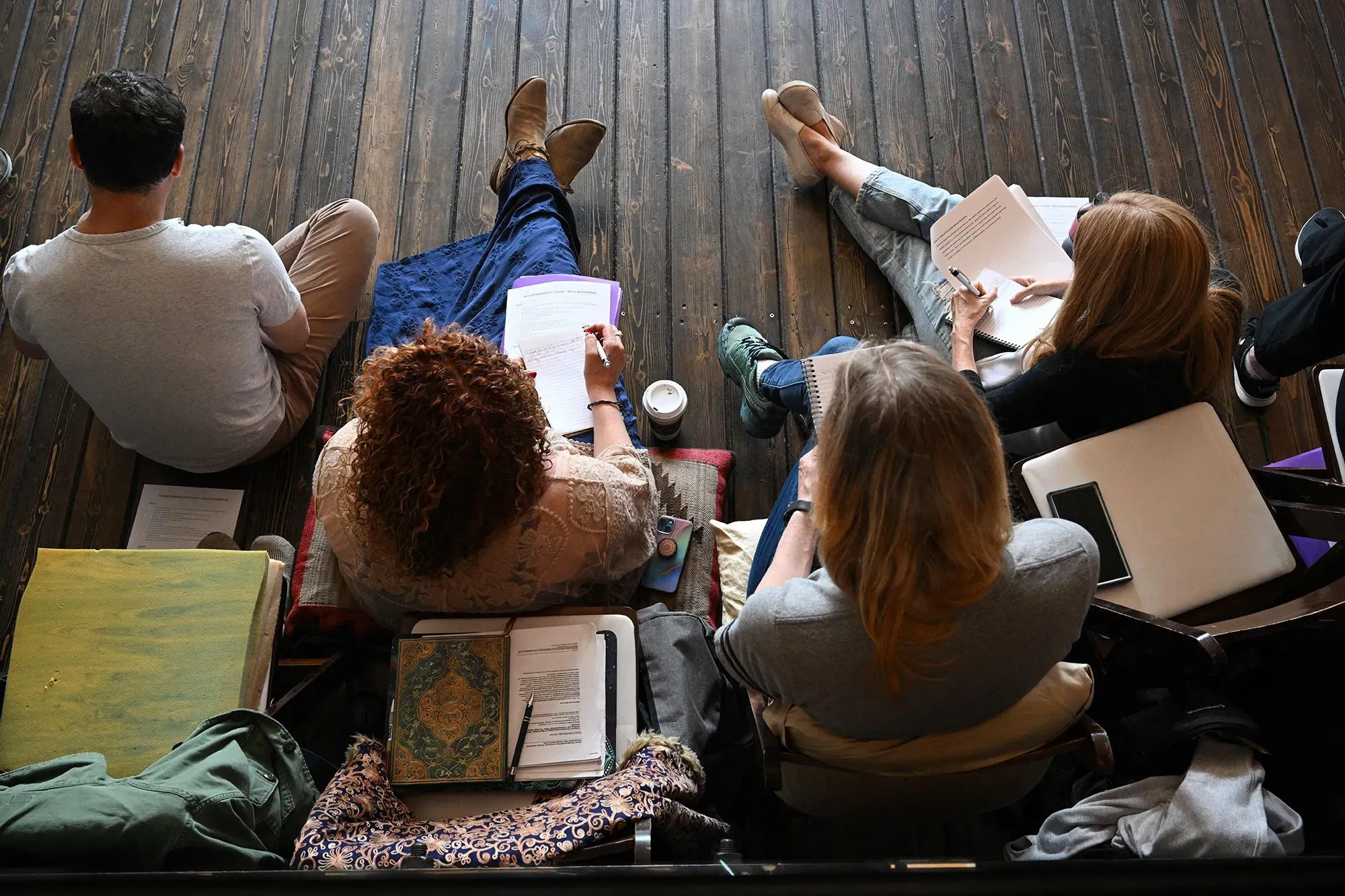 مجموعة من المشاركين يجلسون على الأرض في خلوة، يكتبون ملاحظات حول تجربة تناول السيلوسيبين، مع التركيز على التعافي من الصدمات.