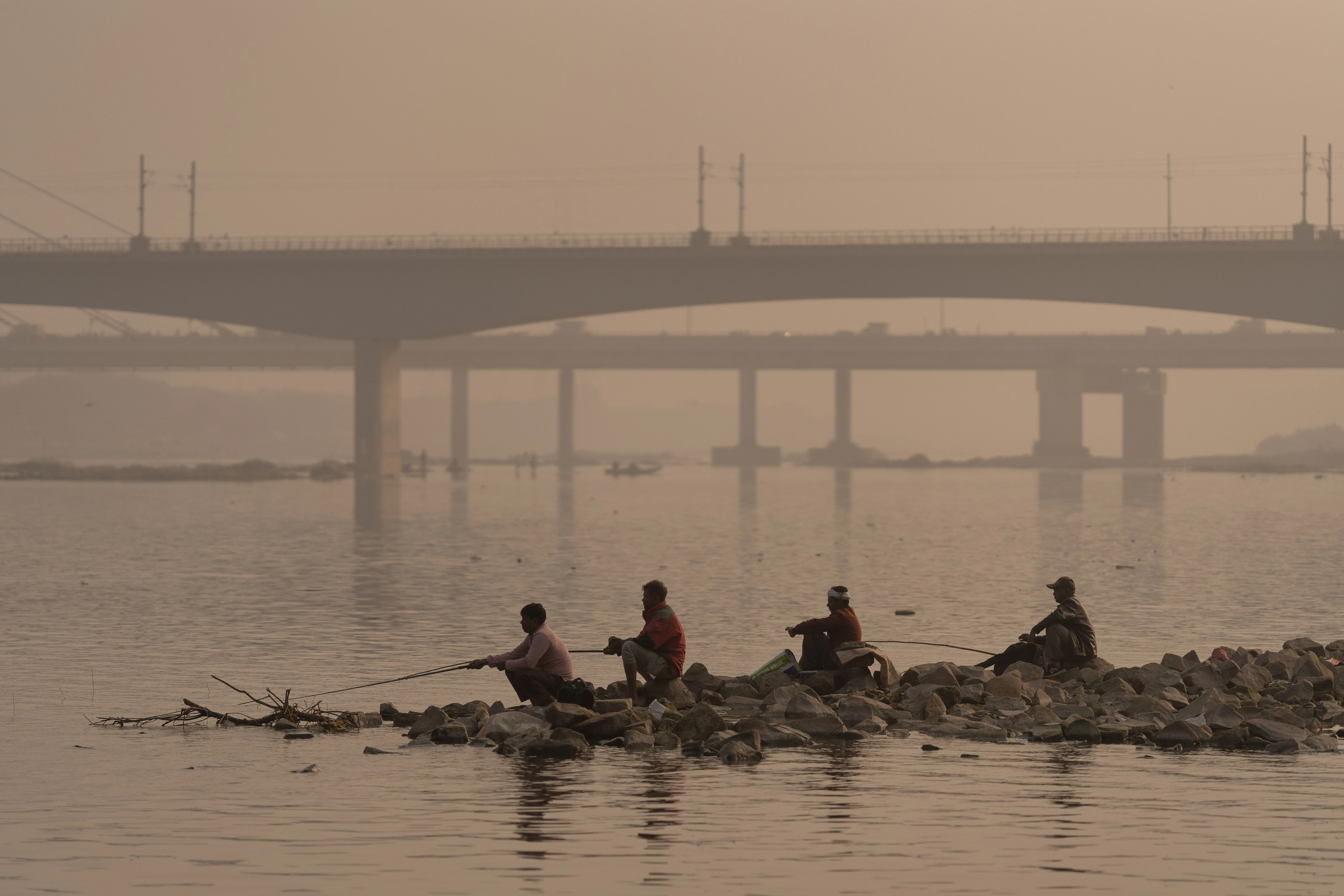 مدينة لوني الهندية تتعرض لتلوث شديد، حيث يظهر الصيادون في النهر تحت ضباب كثيف، مما يعكس أزمة جودة الهواء.