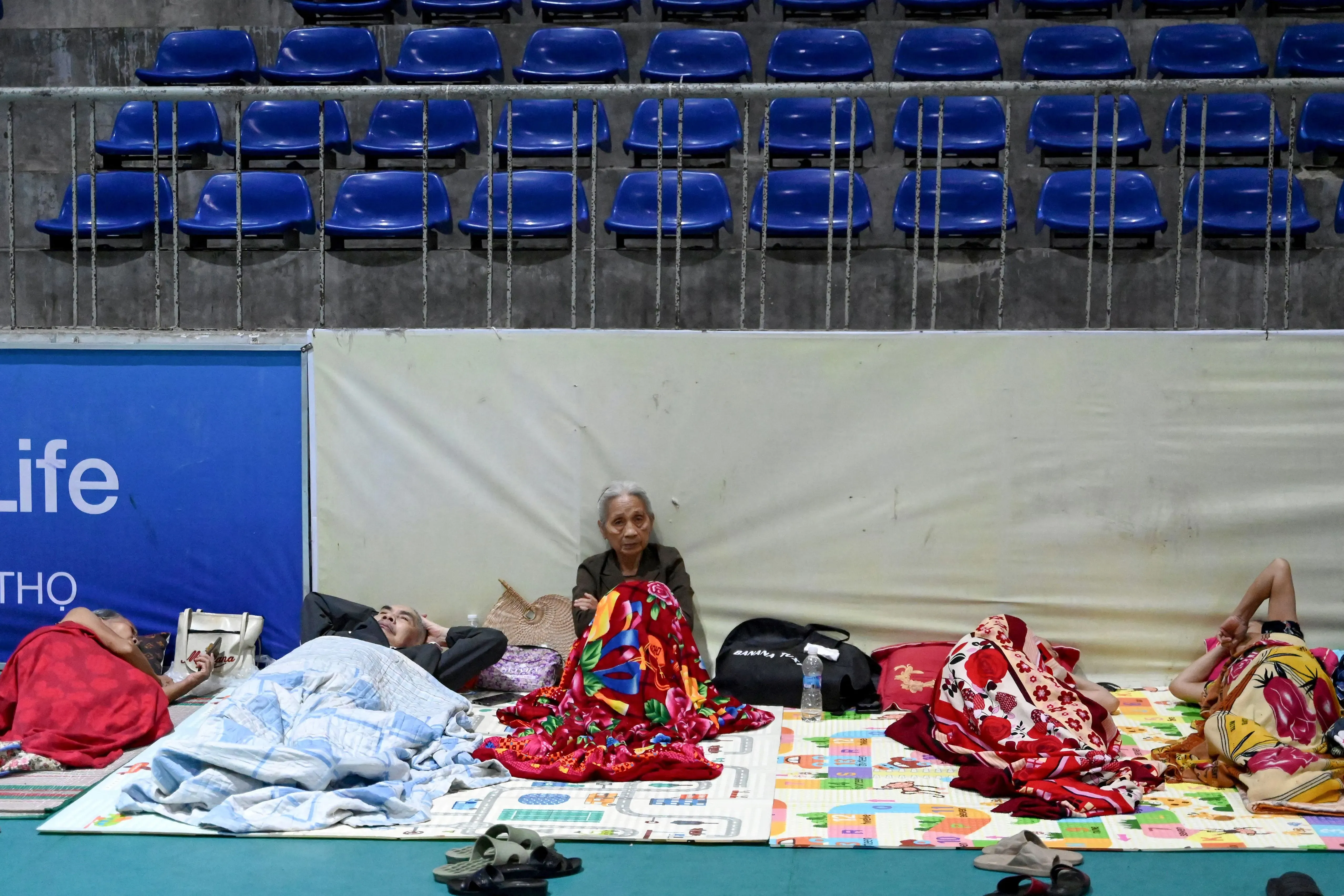 مواطنون في مركز إجلاء في فيتنام يستعدون لوصول إعصار كاجيكي، مع تغطية بعضهم بالأغطية على أرضية الملعب.