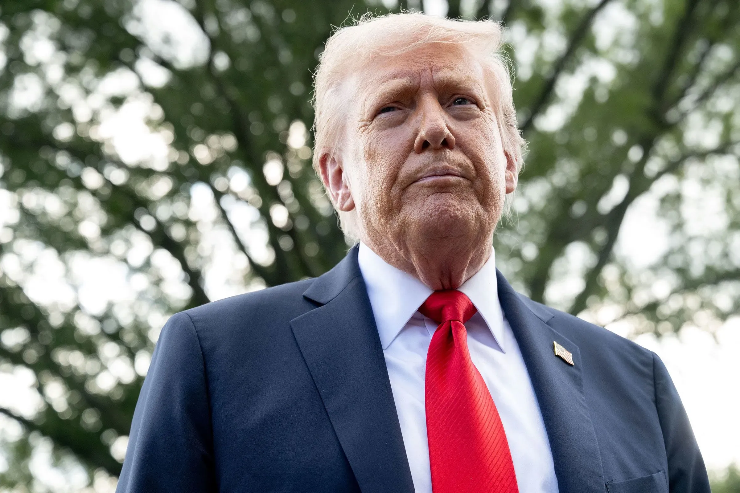 الرئيس الأمريكي السابق دونالد ترامب يتحدث بجدية، مع خلفية طبيعية، خلال مؤتمر صحفي حول قضايا الزراعة والتجارة.