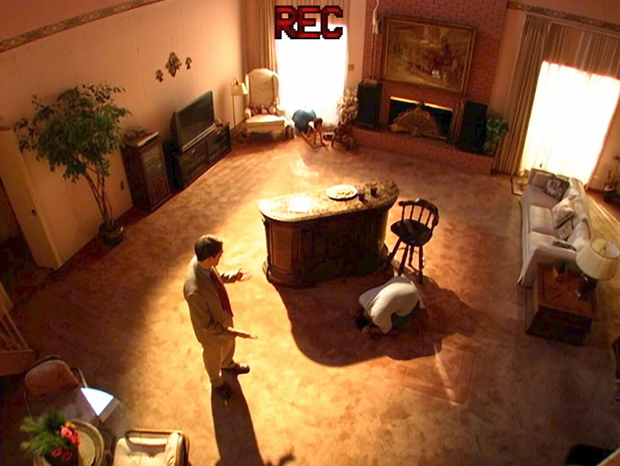 رجل يواجه شخصاً منكسراً على الأرض داخل غرفة معيشة، مشهد من برنامج "To Catch a Predator" يظهر مواجهة كشف مفترس أطفال.