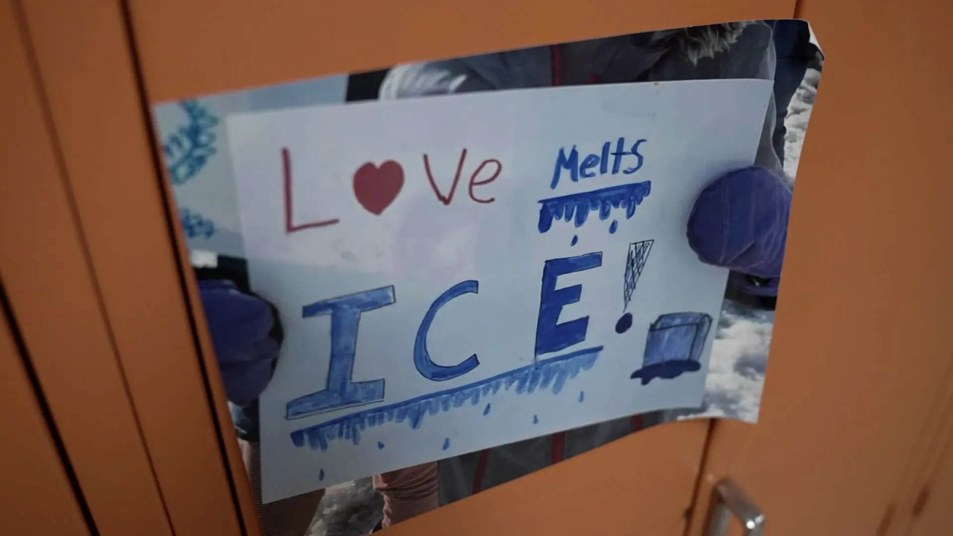 لافتة مكتوبة عليها "الحب يذيب الجليد" مع رسومات ملونة، مثبتة على باب خزانة في مدرسة، تعبر عن دعم الطلاب لمجتمعهم في مواجهة التحديات.