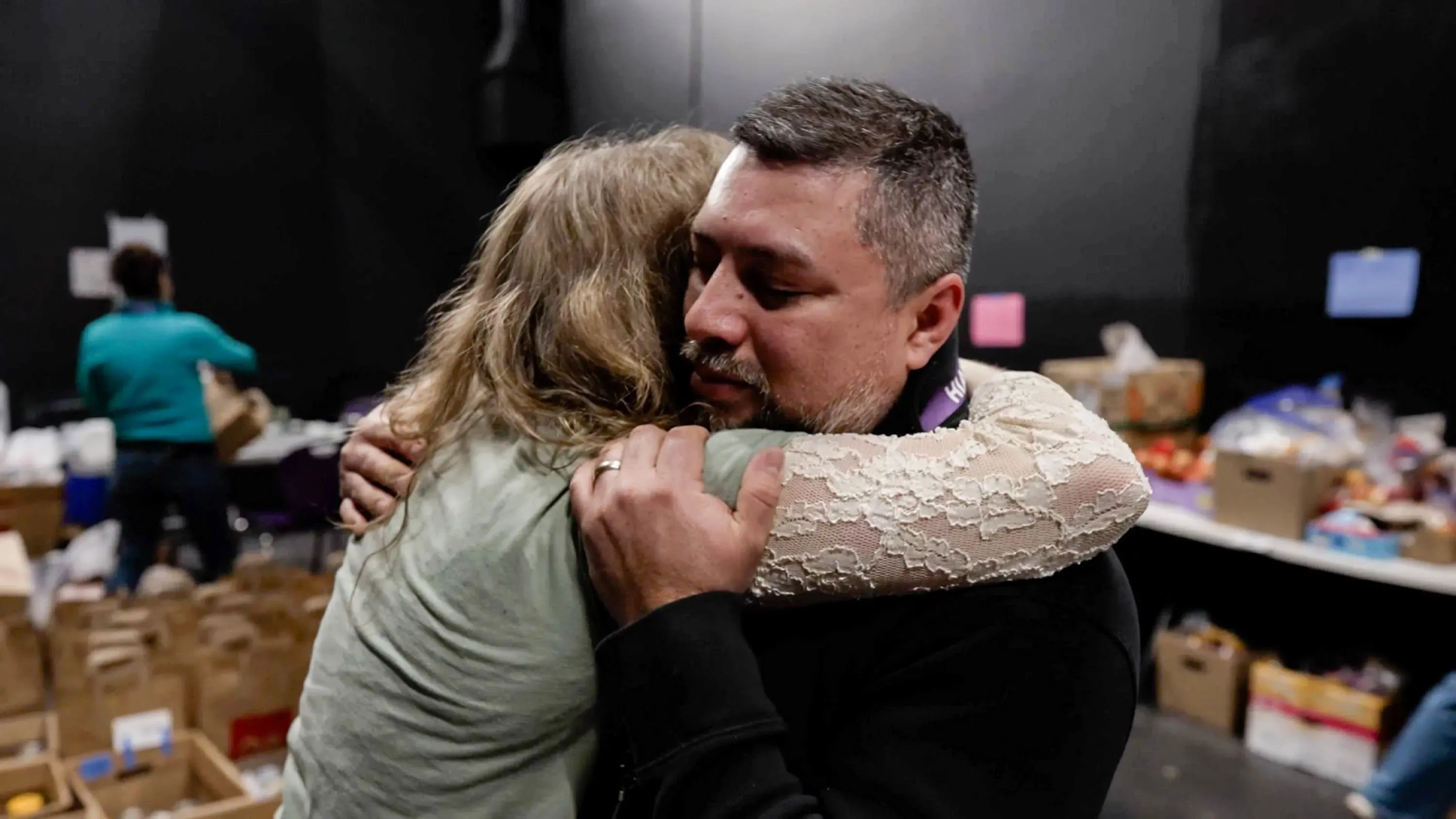 عناق مؤثر بين شخصين في مركز توزيع الطعام، يعكس الدعم المجتمعي وسط القلق من إجراءات الهجرة في مينيابوليس.