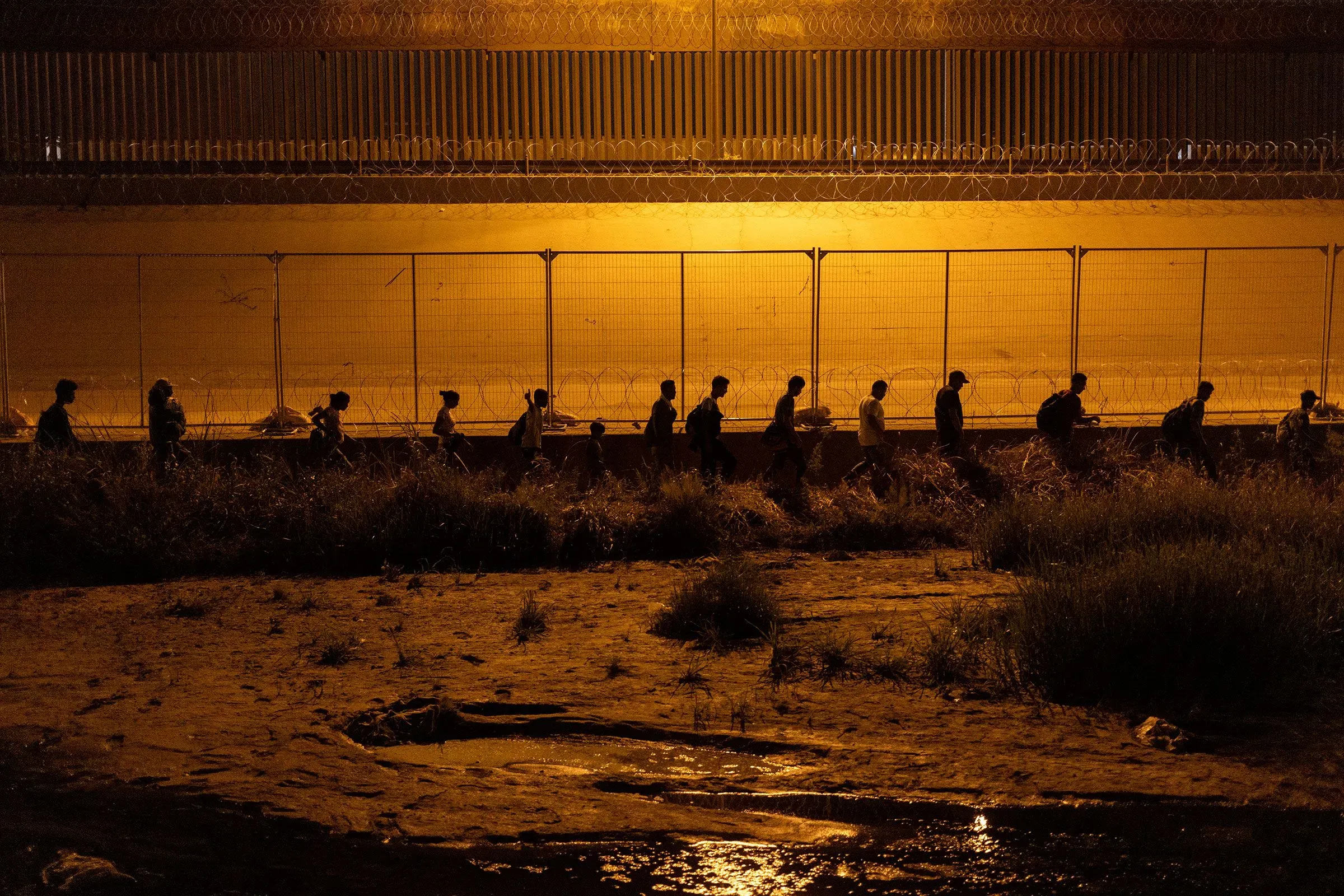 مجموعة من المهاجرين الفنزويليين يسيرون ليلاً بالقرب من الحدود، تحت إضاءة خافتة، في سياق أزمة الهجرة المتزايدة.