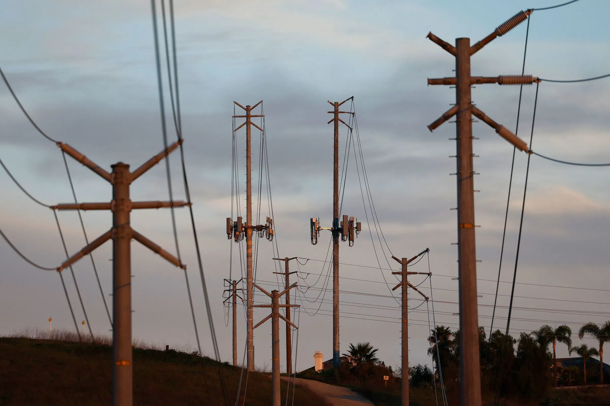 أعمدة كهرباء متجاورة في منطقة ريفية، تعكس التحديات المتزايدة في تكاليف الكهرباء في الولايات المتحدة وتأثيرها على البنية التحتية.