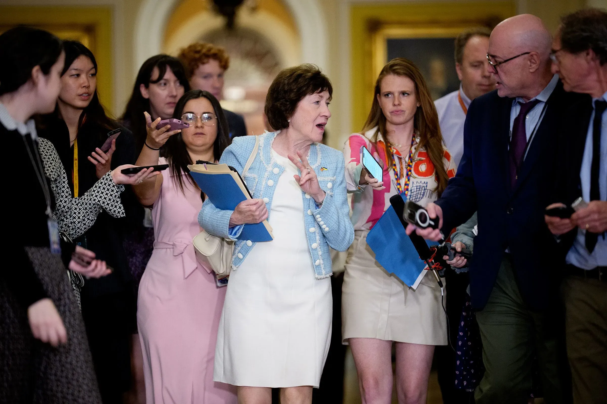 مجموعة من الصحفيين تتجمع حول سياسية تتحدث أثناء مغادرتها مبنى الكونغرس، مما يعكس التوترات حول ميزانية الحكومة.