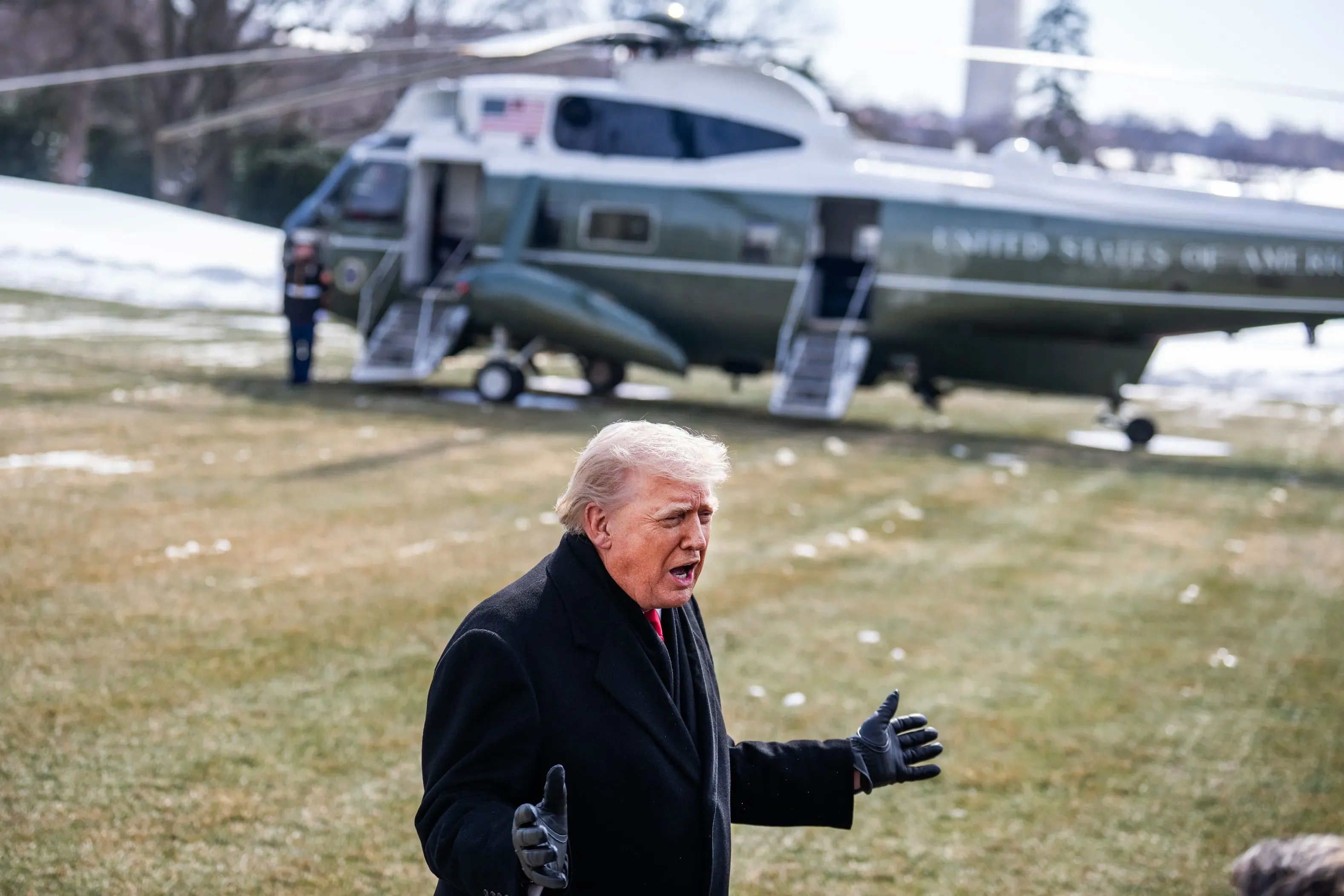 ترامب يتحدث بحماس أمام مروحية تابعة للرئاسة في حديقة البيت الأبيض، مع خلفية ثلجية تعكس الأجواء الشتوية.