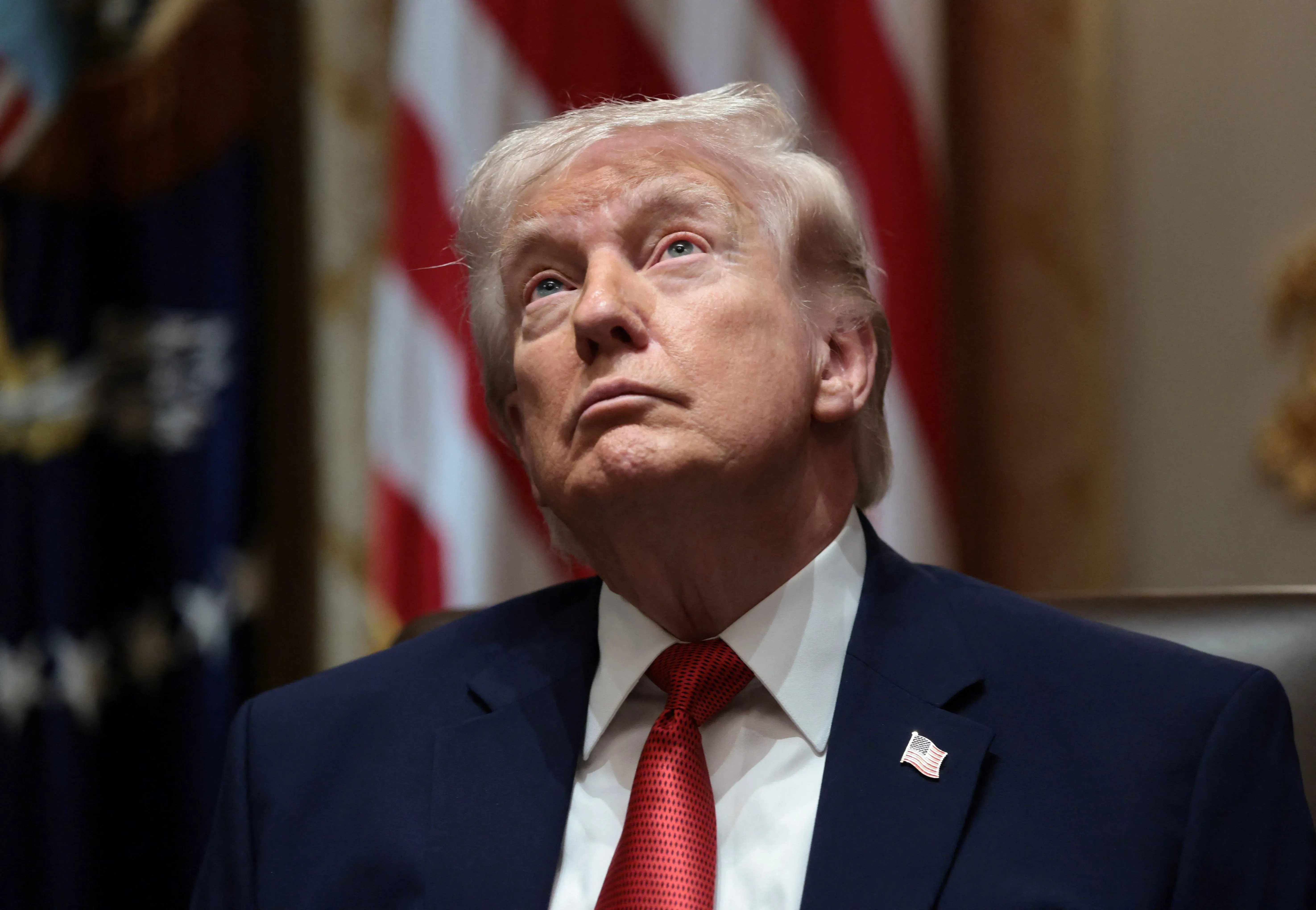 ترامب ينظر للأعلى أثناء حديثه عن تمويل إدارة أمن النقل، مع العلم بوجود أعلام خلفه، مما يعكس حالة القلق حول رواتب الموظفين.