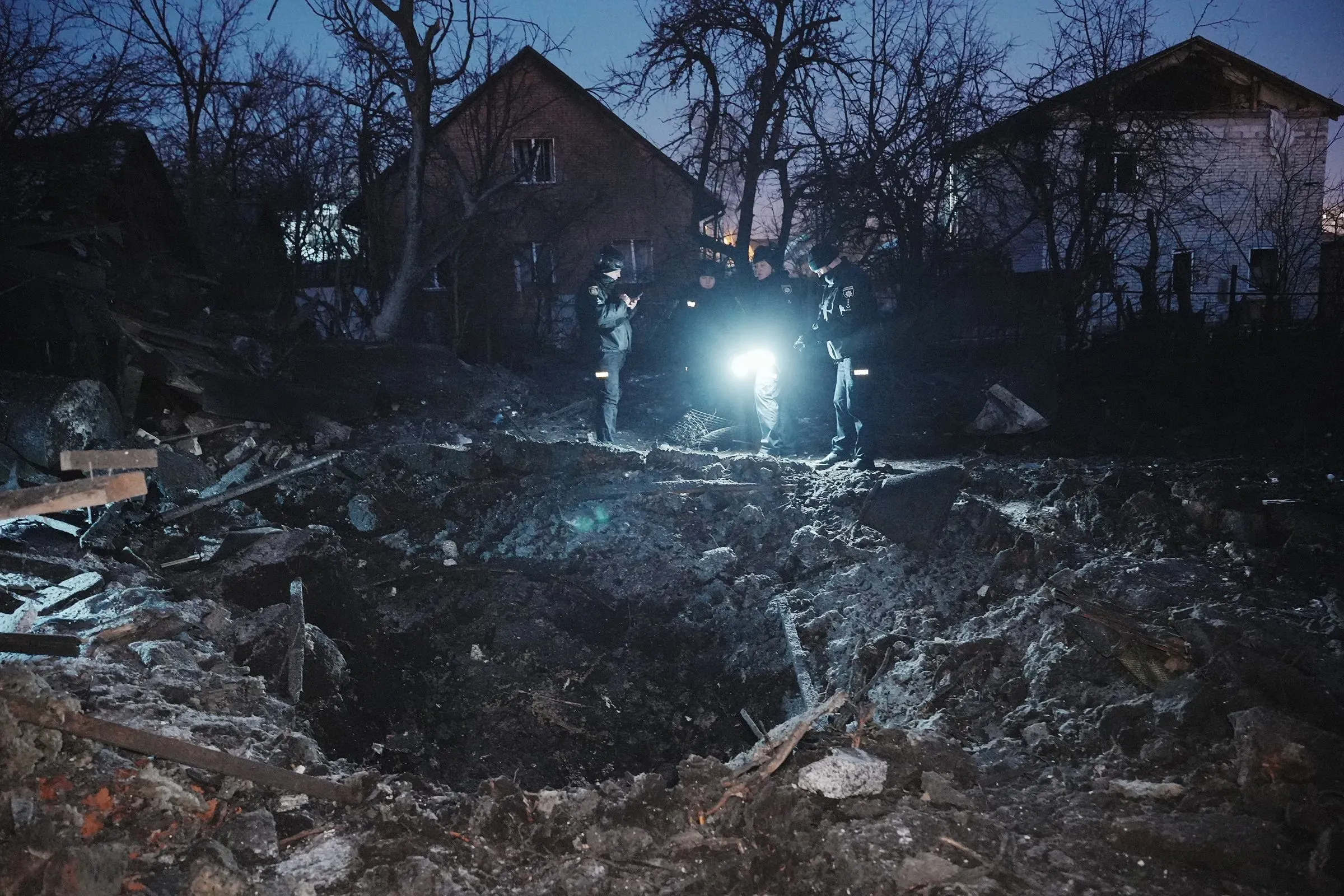 موقع تفجير في أوكرانيا، حيث يقوم رجال الإنقاذ بتفقد الأضرار في موقع الهجوم، مع بقايا الحطام في الخلفية.