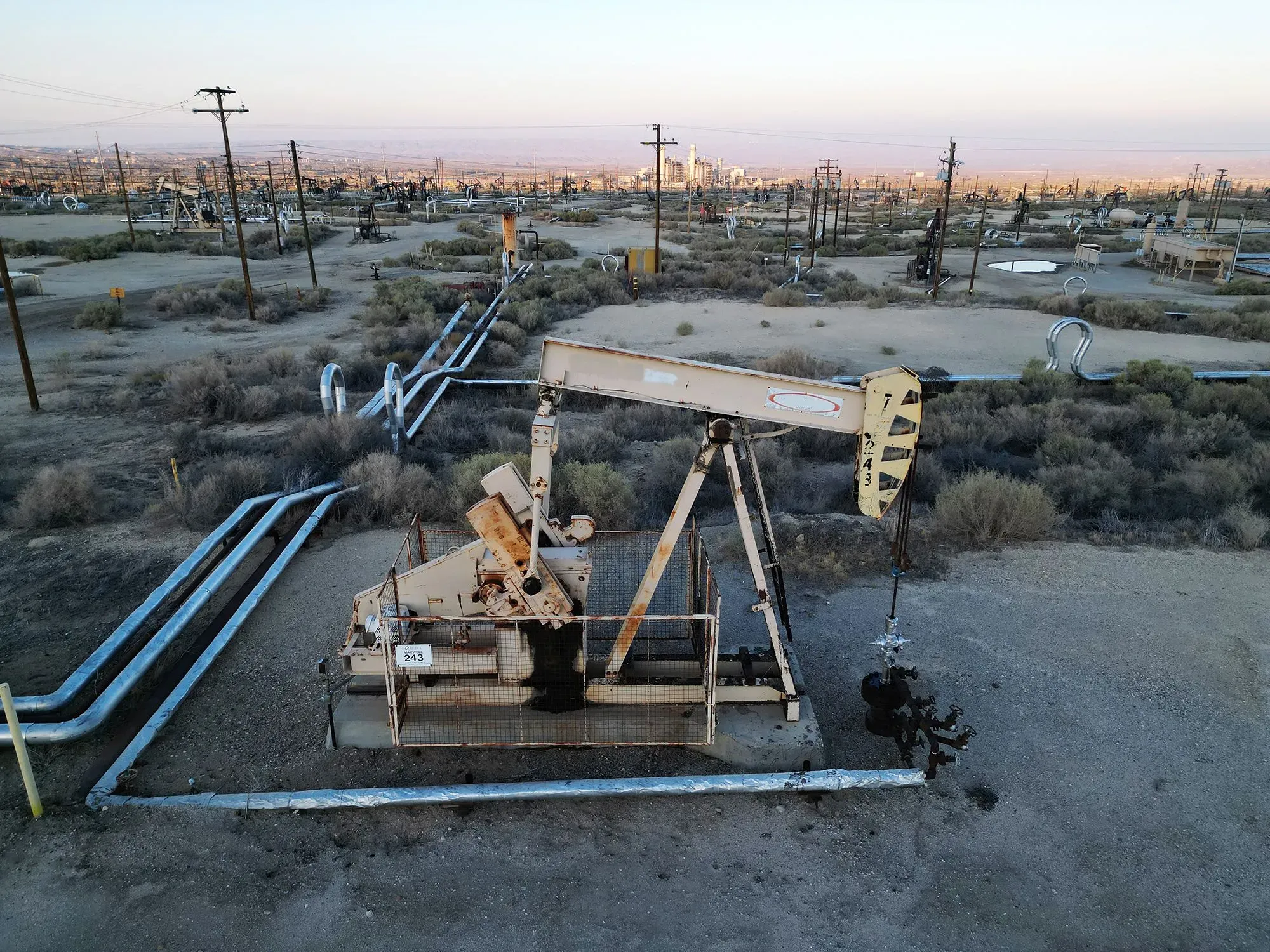 مضخة نفط قديمة في منطقة صحراوية، مع أنابيب نفطية ممدودة في الخلفية، تعكس تدهور صناعة النفط في فنزويلا.