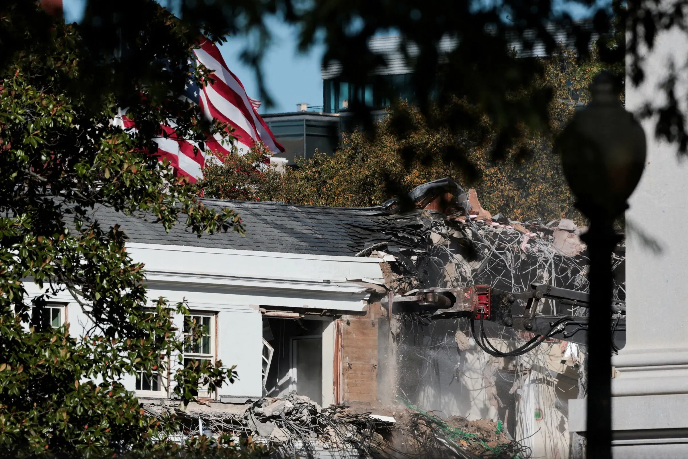 عملية هدم الجناح الشرقي للبيت الأبيض، مع ظهور علم الولايات المتحدة في الخلفية، تعكس المشروع الجريء لبناء قاعة احتفالات جديدة.