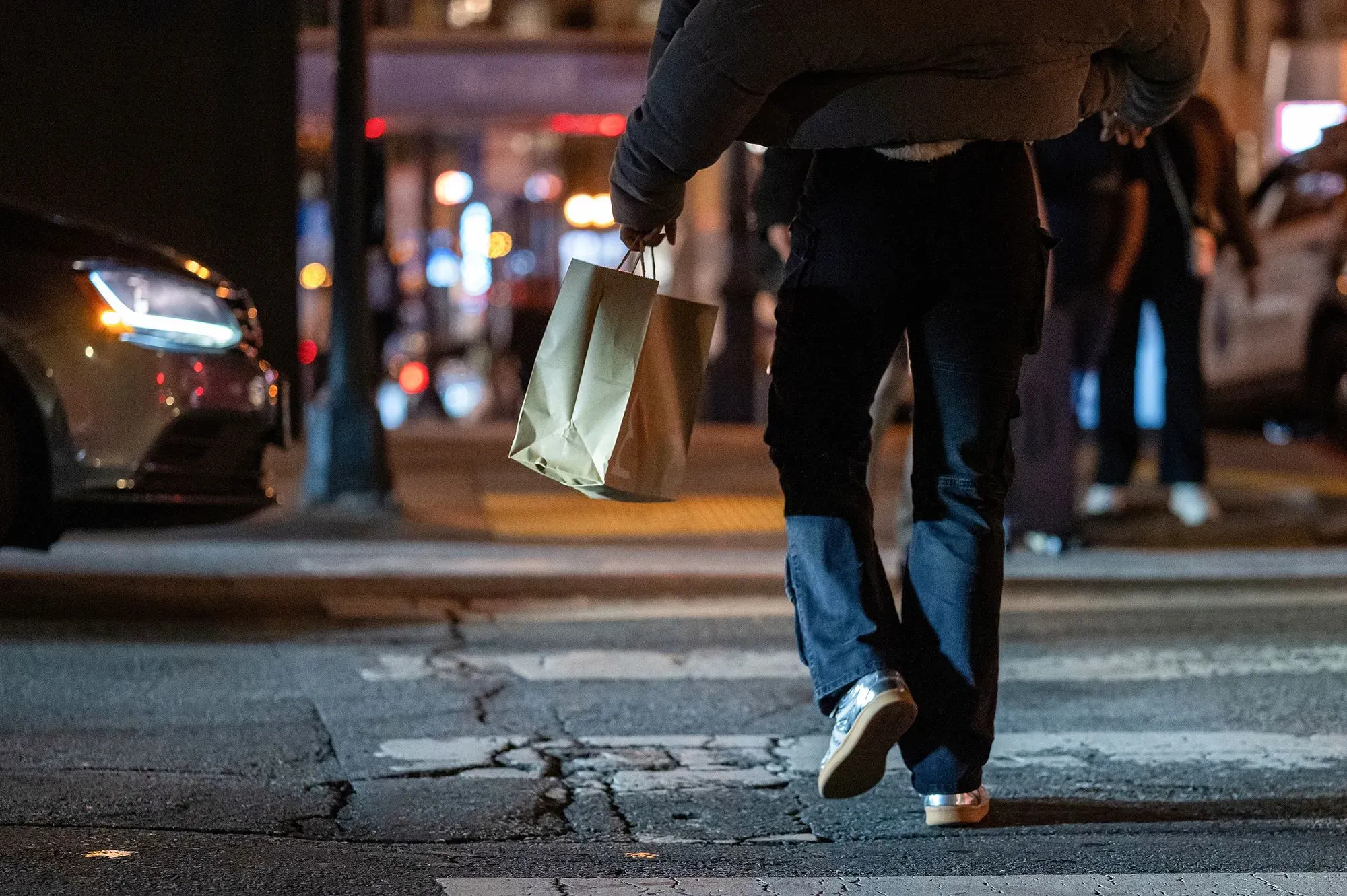 شخص يحمل حقيبة تسوق في الشارع ليلاً، مما يعكس تأثير تكاليف المعيشة على الأمريكيين في ظل النقاشات الاقتصادية الحالية.