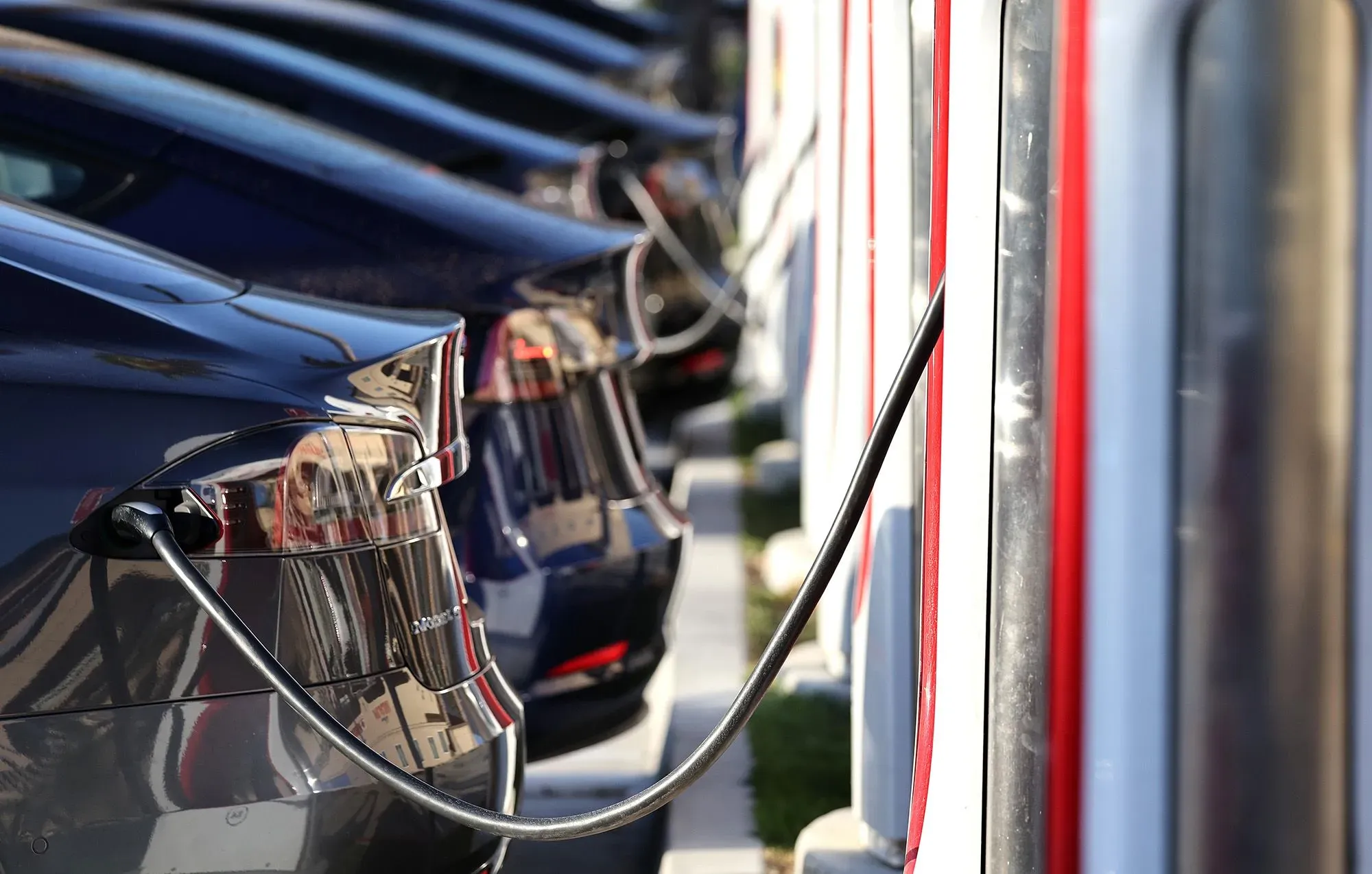 سيارات كهربائية متصلة بشواحن في محطة شحن، تظهر تزايد الاعتماد على السيارات الكهربائية وسط تغييرات في لوائح الانبعاثات.