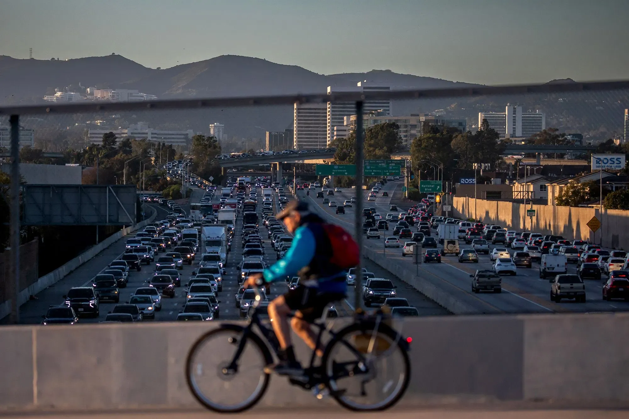 ازدحام مروري كثيف على الطريق السريع مع راكب دراجة في المقدمة، مما يعكس التغيرات في صناعة السيارات وتأثيرها على التنقل.