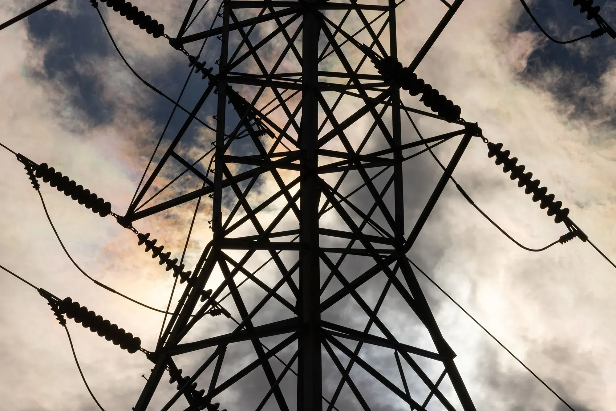 برج كهرباء مرتفع مع أسلاك تحمل الطاقة، يبرز في سماء ملبدة بالغيوم، يعكس زيادة الطلب على الطاقة بسبب الذكاء الاصطناعي.