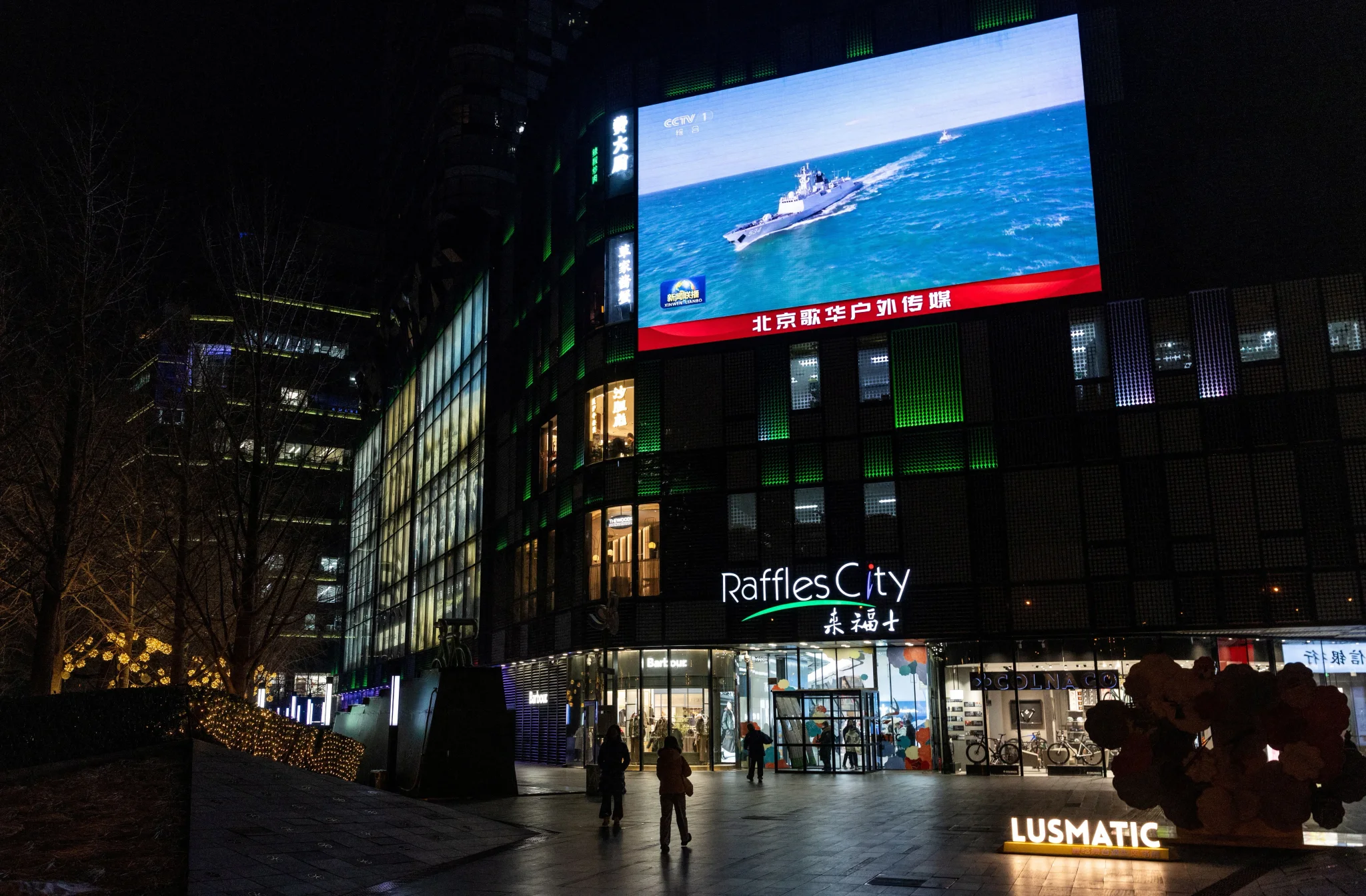 واجهة مبنى "Raffles City" في بكين، مع شاشة عرض كبيرة تعرض مشهدًا بحريًا، تعكس أجواء الزيارة الرسمية للرئيس ترامب.