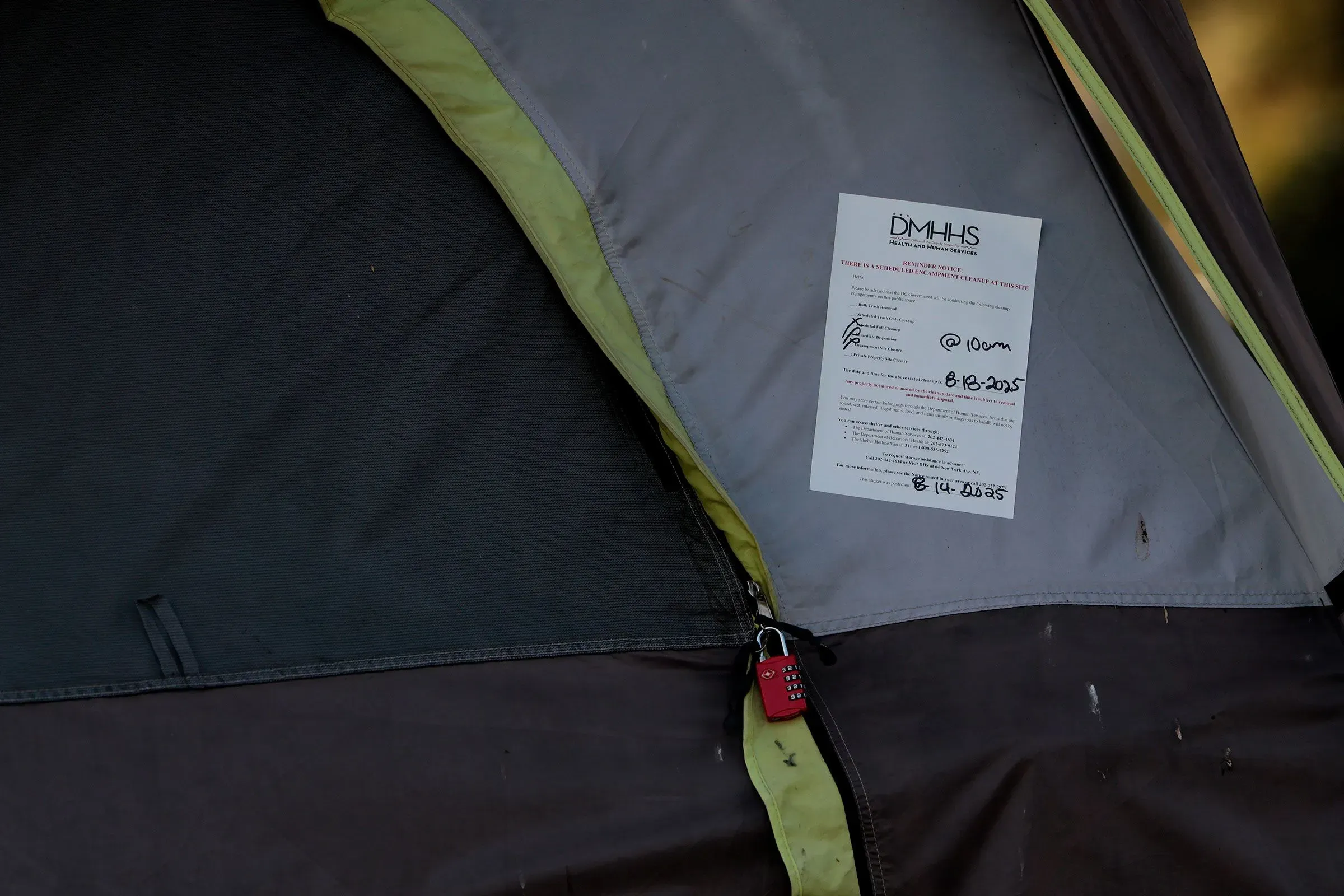 ورقة مرفقة على خيمة مشرد، تحتوي على معلومات تتعلق بالإخلاء، مع قفل أحمر على سحاب الخيمة، تعكس الوضع الصعب للمشردين في العاصمة.