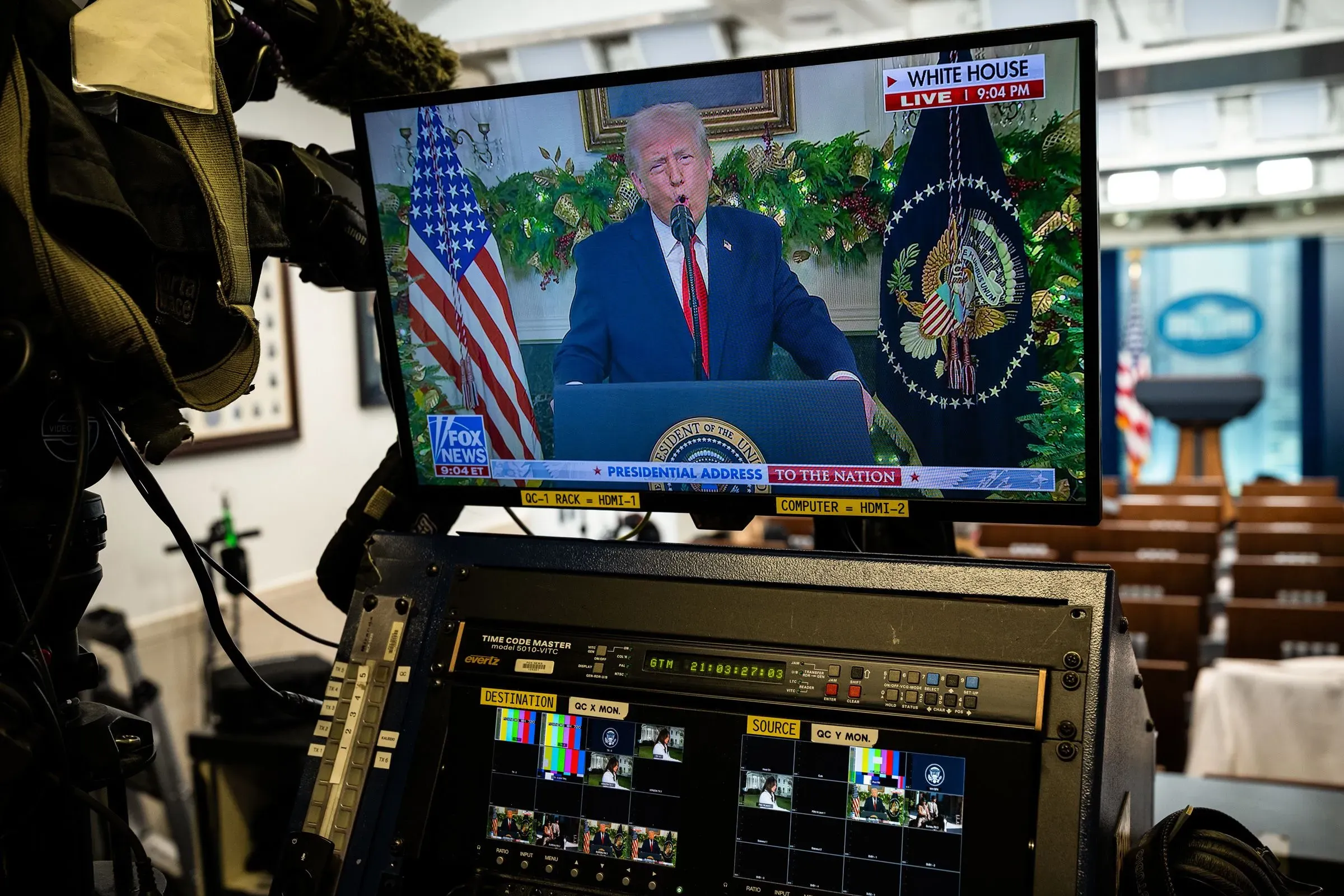 ترامب يلقي خطابًا في البيت الأبيض، مع خلفية مزينة بأشجار عيد الميلاد، وسط أجواء سياسية متوترة تعكس تراجع شعبيته.