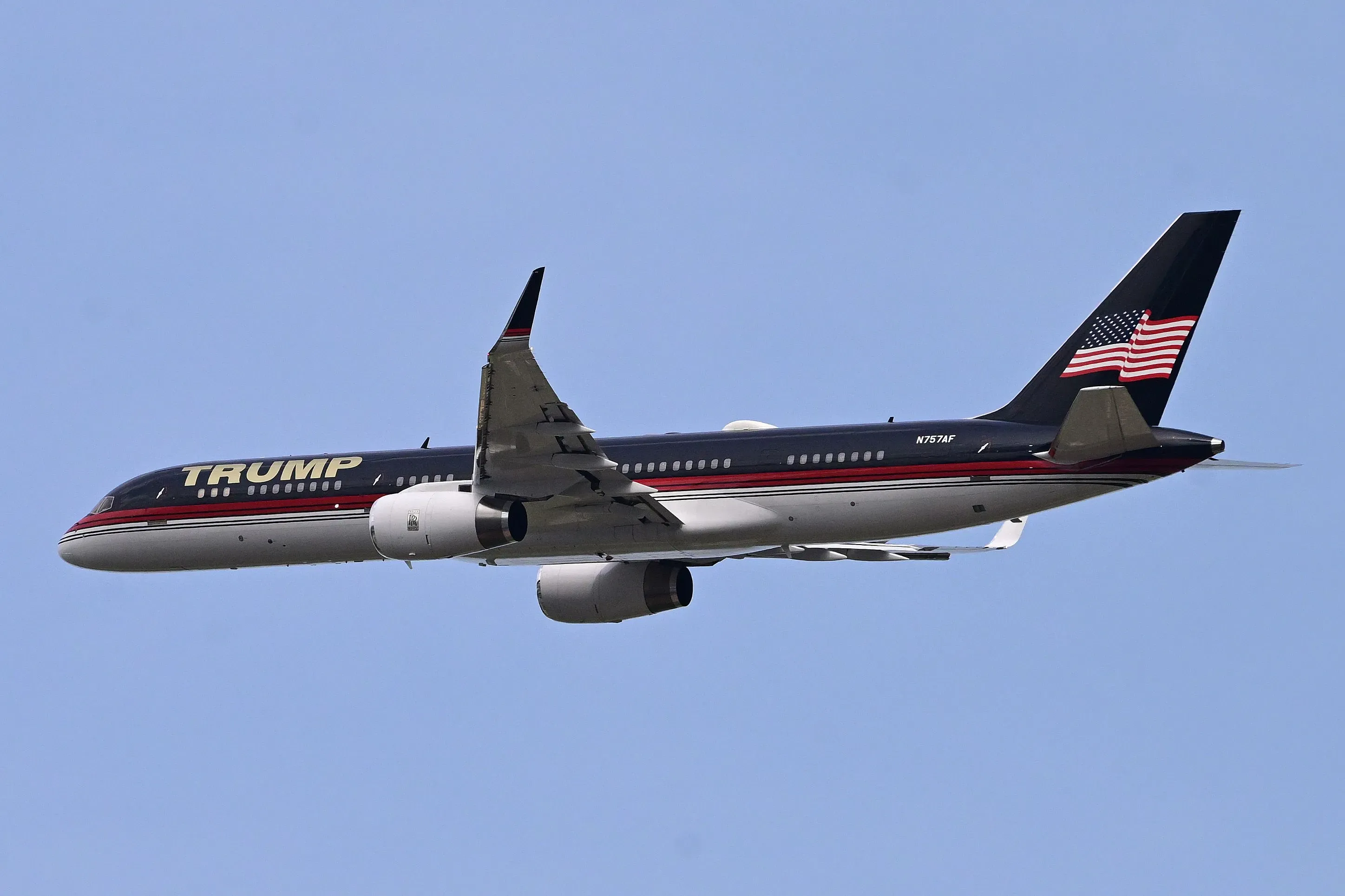 طائرة بوينج 757 الخاصة بدونالد ترامب، مزينة بشعار "ترامب" وعلم الولايات المتحدة، تحلق في السماء.