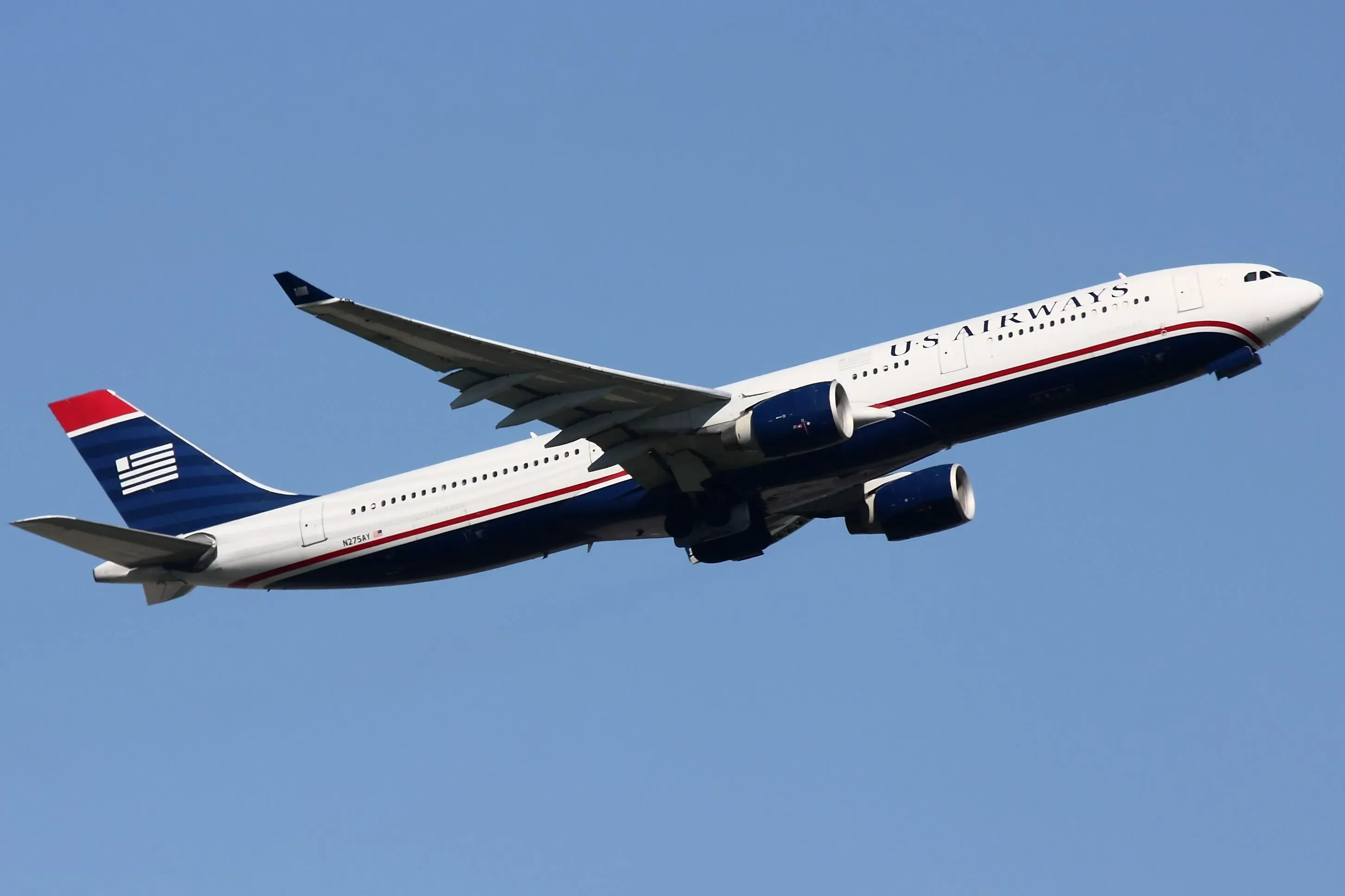 طائرة تجارية تابعة لشركة يو إس إيروايز في السماء، تظهر تصميمها بالألوان الحمراء والزرقاء، مما يبرز تشابهها مع مخطط طلاء الطائرات الرئاسية.