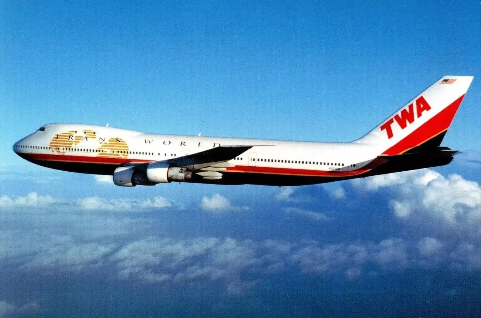 طائرة بوينج 747-800 تابعة لشركة ترانس وورلد إيرلاينز، مزينة بالألوان الأحمر والأبيض والذهبي، تحلق في السماء.