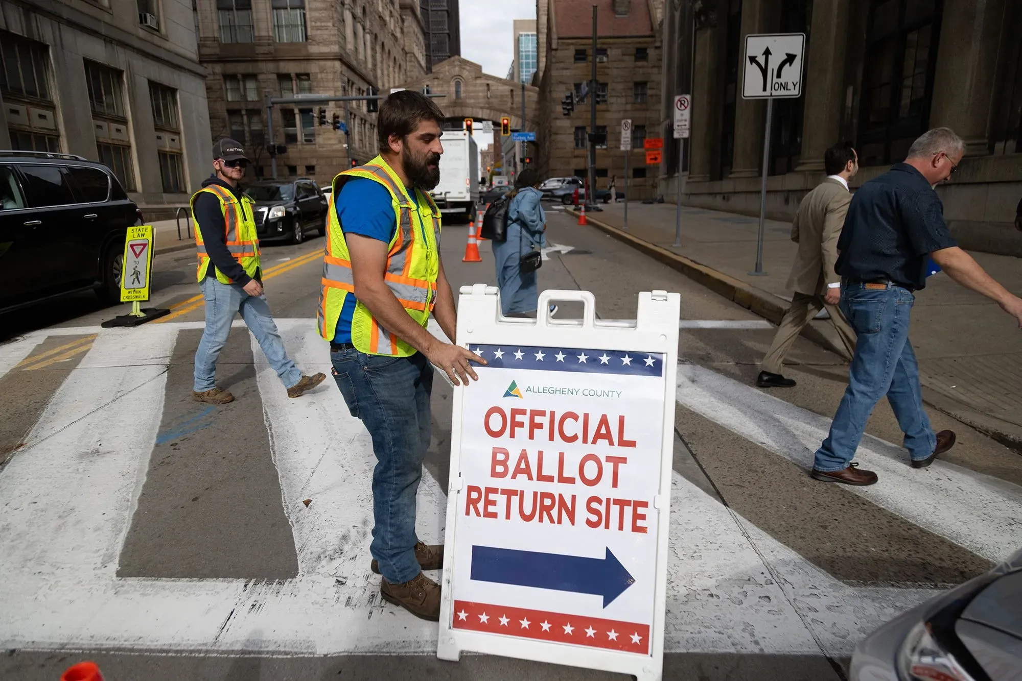 موقع رسمي لإعادة بطاقات الاقتراع في ولاية أليغيني، مع أشخاص يرتدون سترات عاكسة، يعكس أهمية التصويت عبر البريد في الانتخابات.