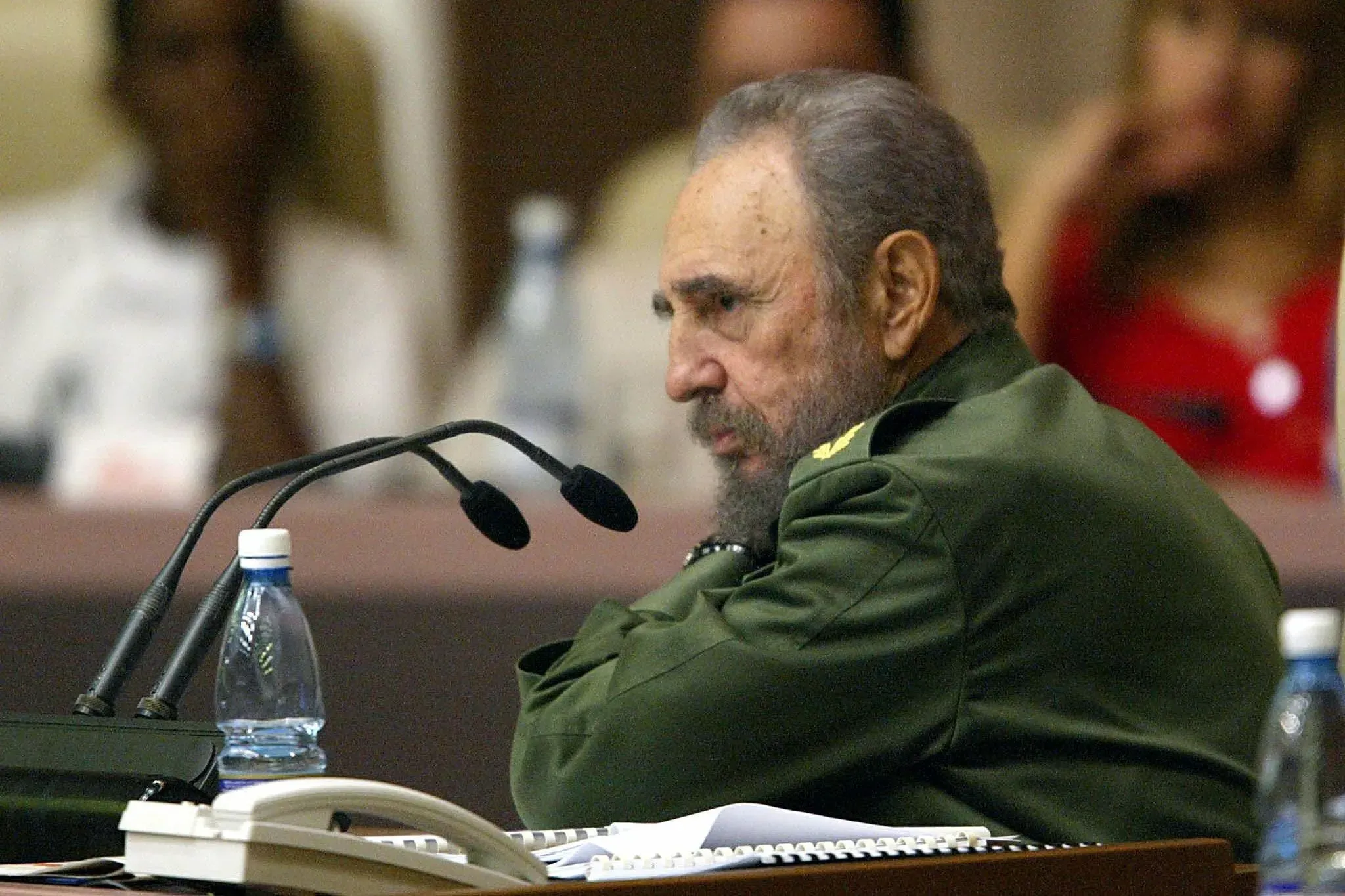 في الصورة، فيدل كاسترو يتحدث خلال اجتماع، مع التركيز على تعبير وجهه الجاد. تعكس الصورة السياق التاريخي للتدخلات الأمريكية في أمريكا اللاتينية.