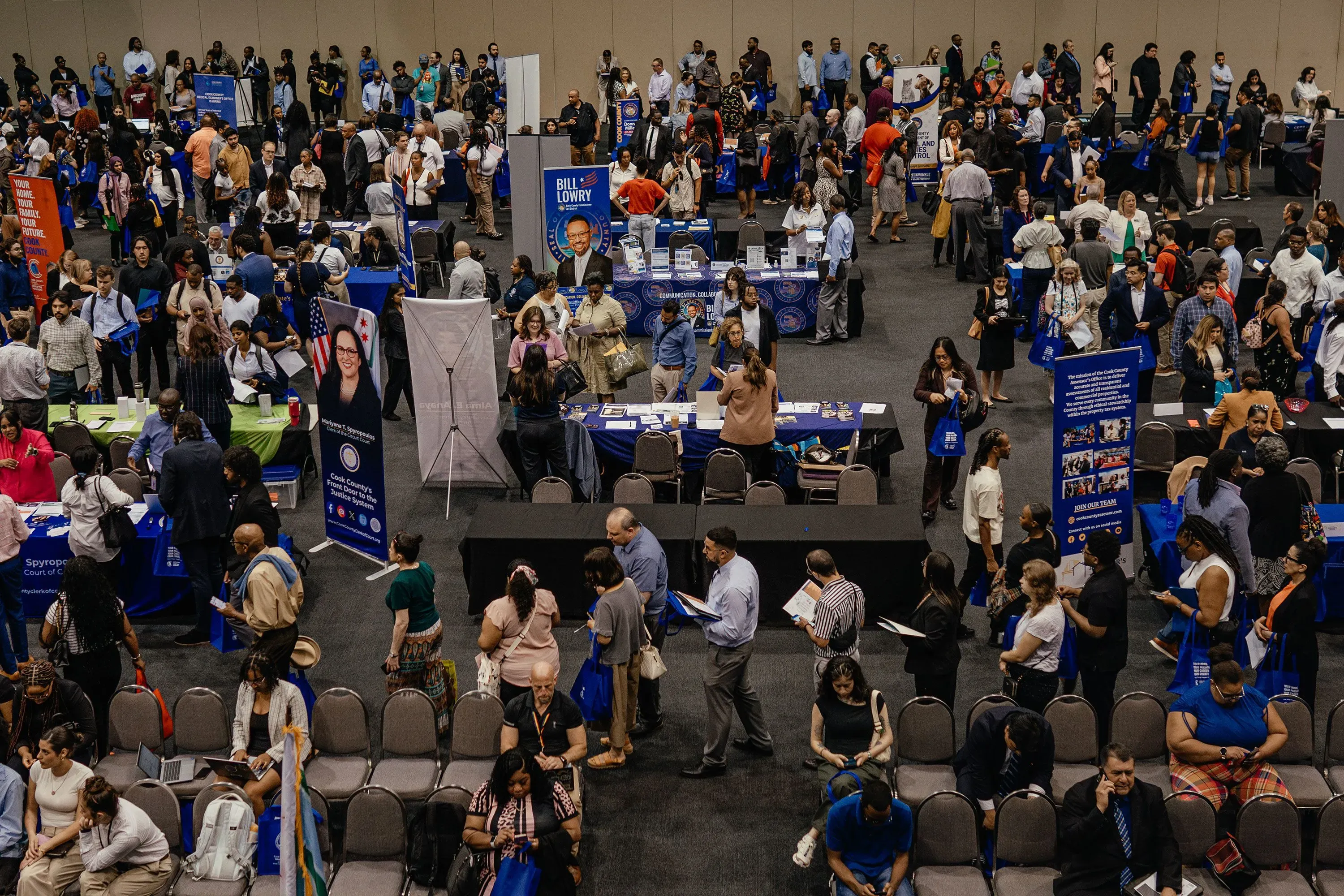 تجمع حاشد في معرض توظيف، حيث يتفاعل المشاركون مع ممثلي الشركات. يظهر خلفهم لافتات دعائية ومعلومات عن الوظائف المتاحة.