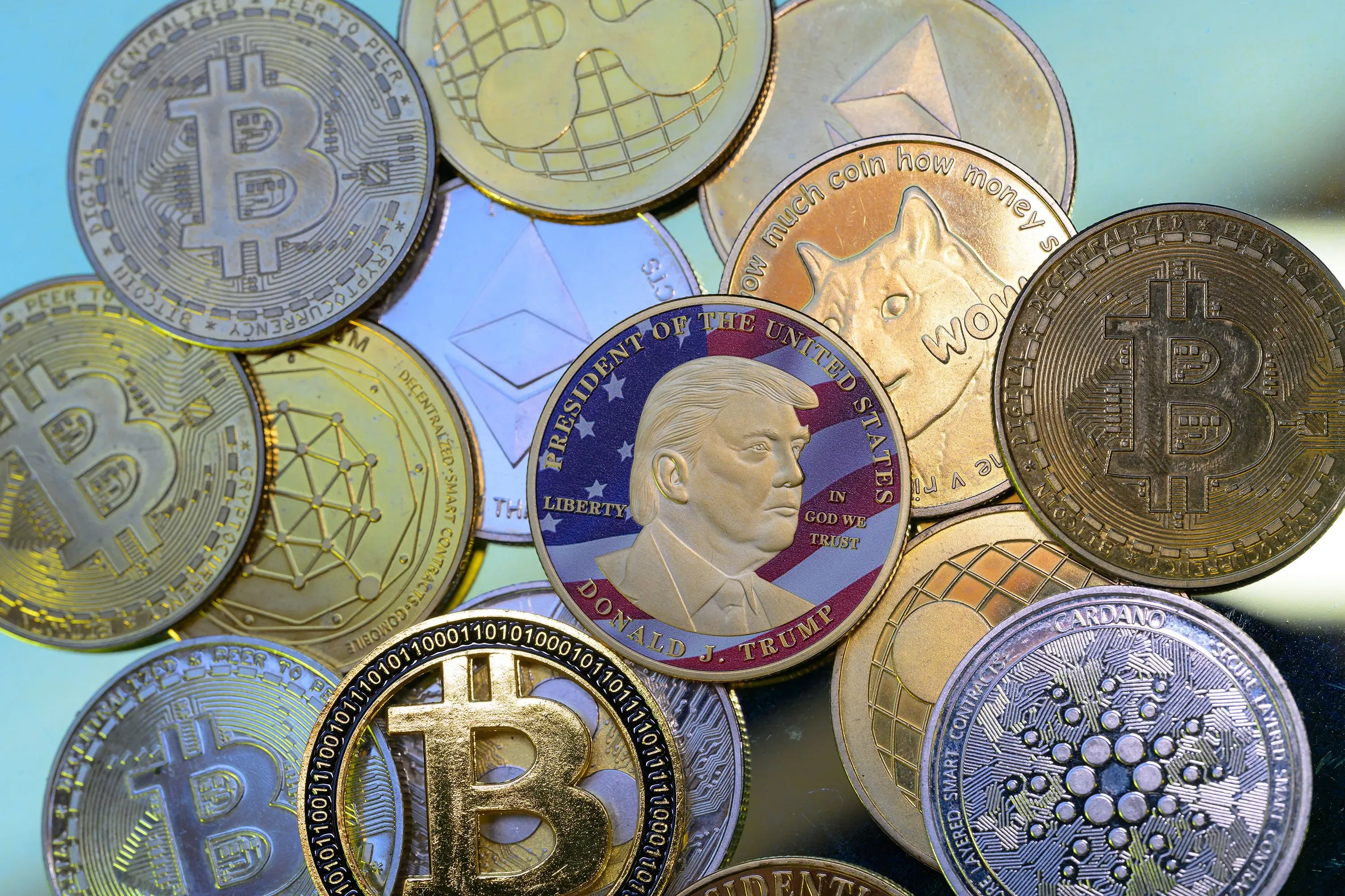 مجموعة من العملات المشفرة، بما في ذلك بيتكوين وإيثيريوم، مع عملة تذكارية تحمل صورة الرئيس ترامب، تعكس اهتمامه بالاستثمارات الرقمية.