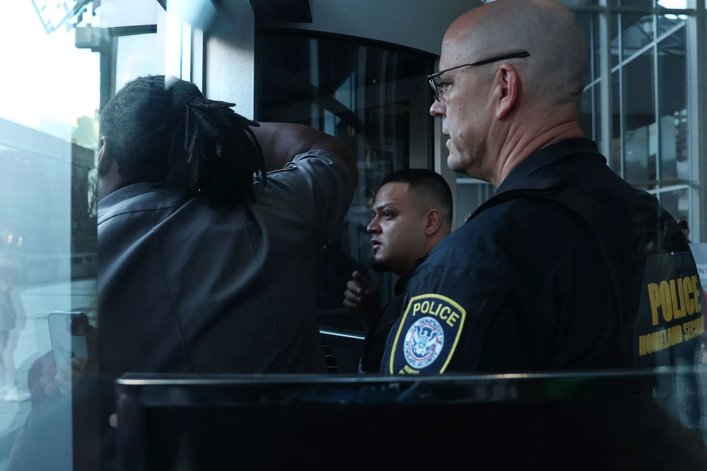 مشهد يظهر ضباط إنفاذ القانون يتفاعلون مع شخص في موقع حساس، مما يعكس الأجواء المتوترة المتعلقة بالتحقيقات القانونية في إدارة ترامب.