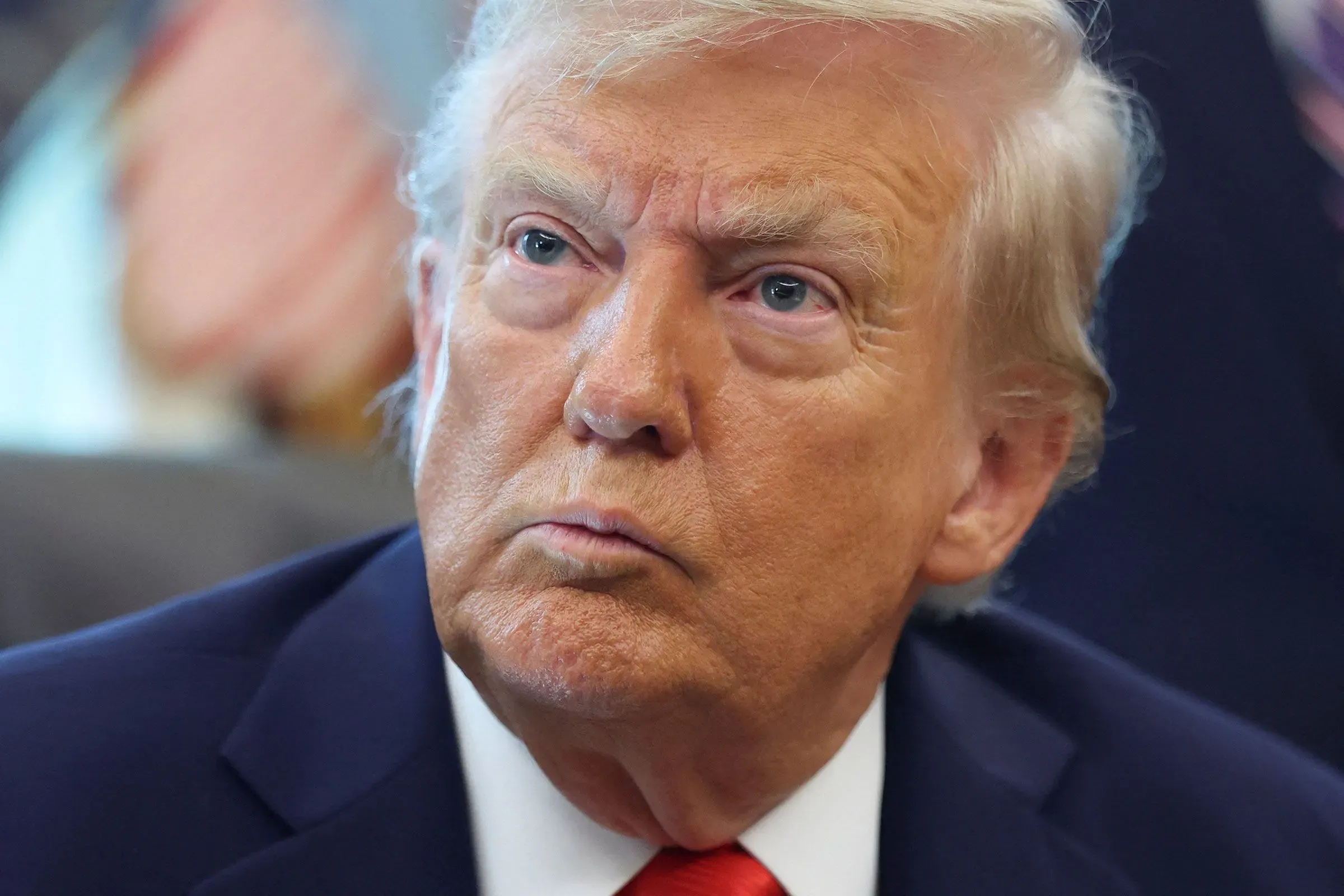 صورة مقربة للرئيس الأمريكي السابق دونالد ترامب، تظهر تعابير وجهه الجادة أثناء حديثه في اجتماع.