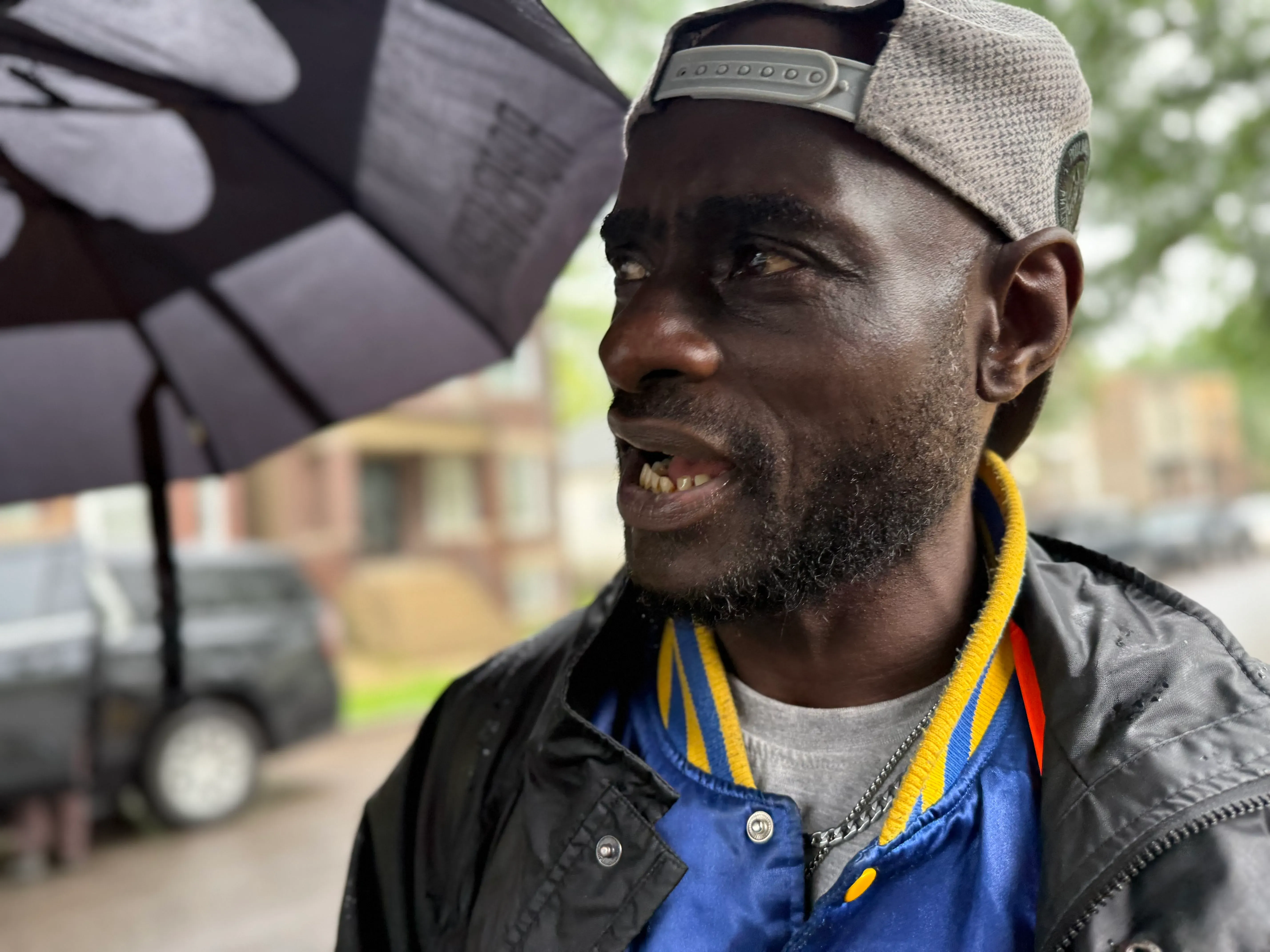 رجل يتحدث تحت مظلة في شيكاغو، يعكس مشاعر الغضب والألم بعد تجربة اعتقاله. تفاصيل تعكس معاناته بعد التعذيب من قبل الشرطة.