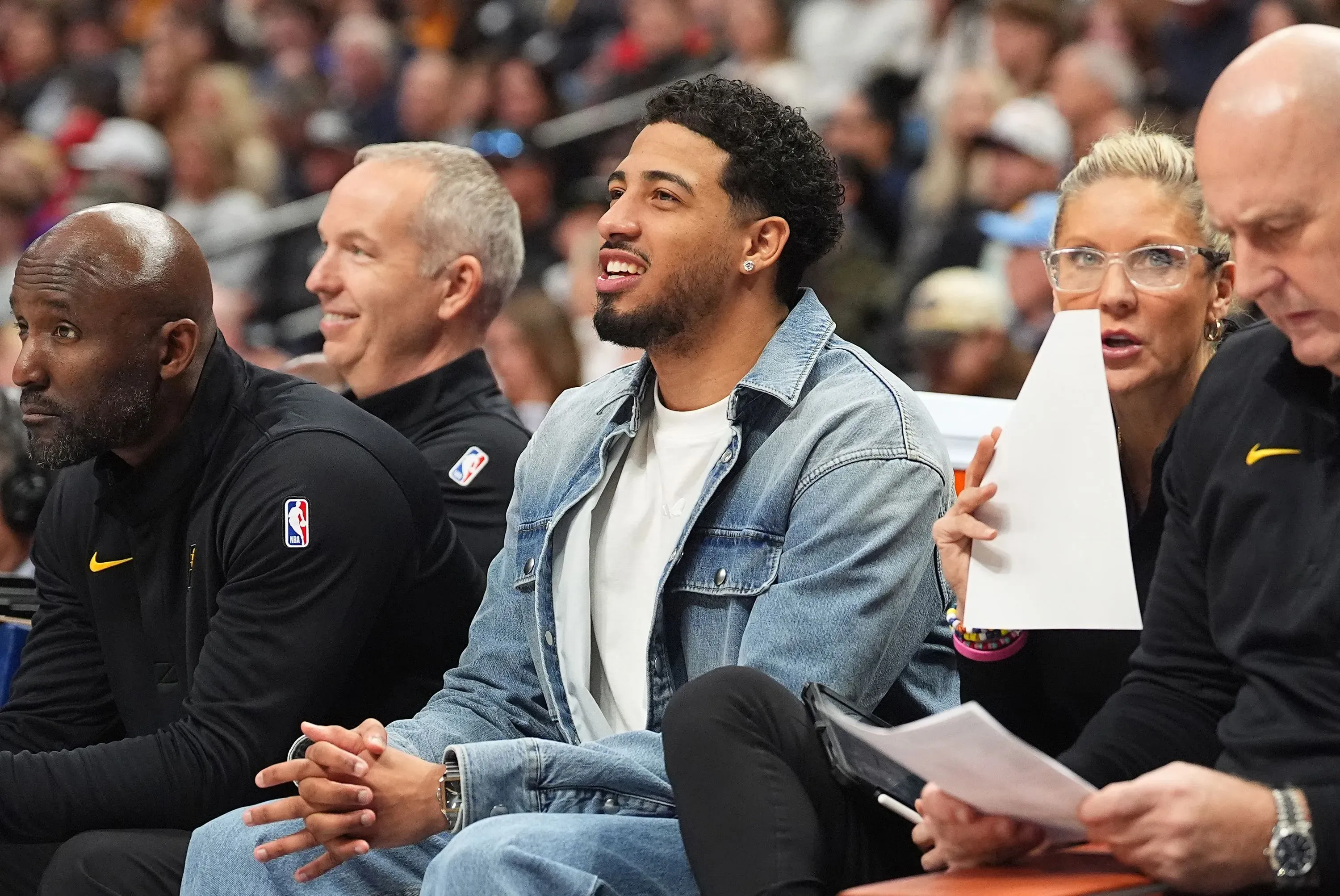 تايريس هاليبرتون يجلس على مقاعد البدلاء في مباراة كرة سلة، مبتسمًا مع زملائه، مما يعكس روح الفريق والتعاون في موسم 2024-25.