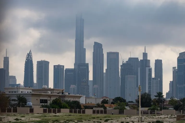 أفق مدينة دبي مع ناطحات سحاب بارزة مثل برج خليفة، تحت سماء غائمة، مما يعكس التوترات الإقليمية الحالية.