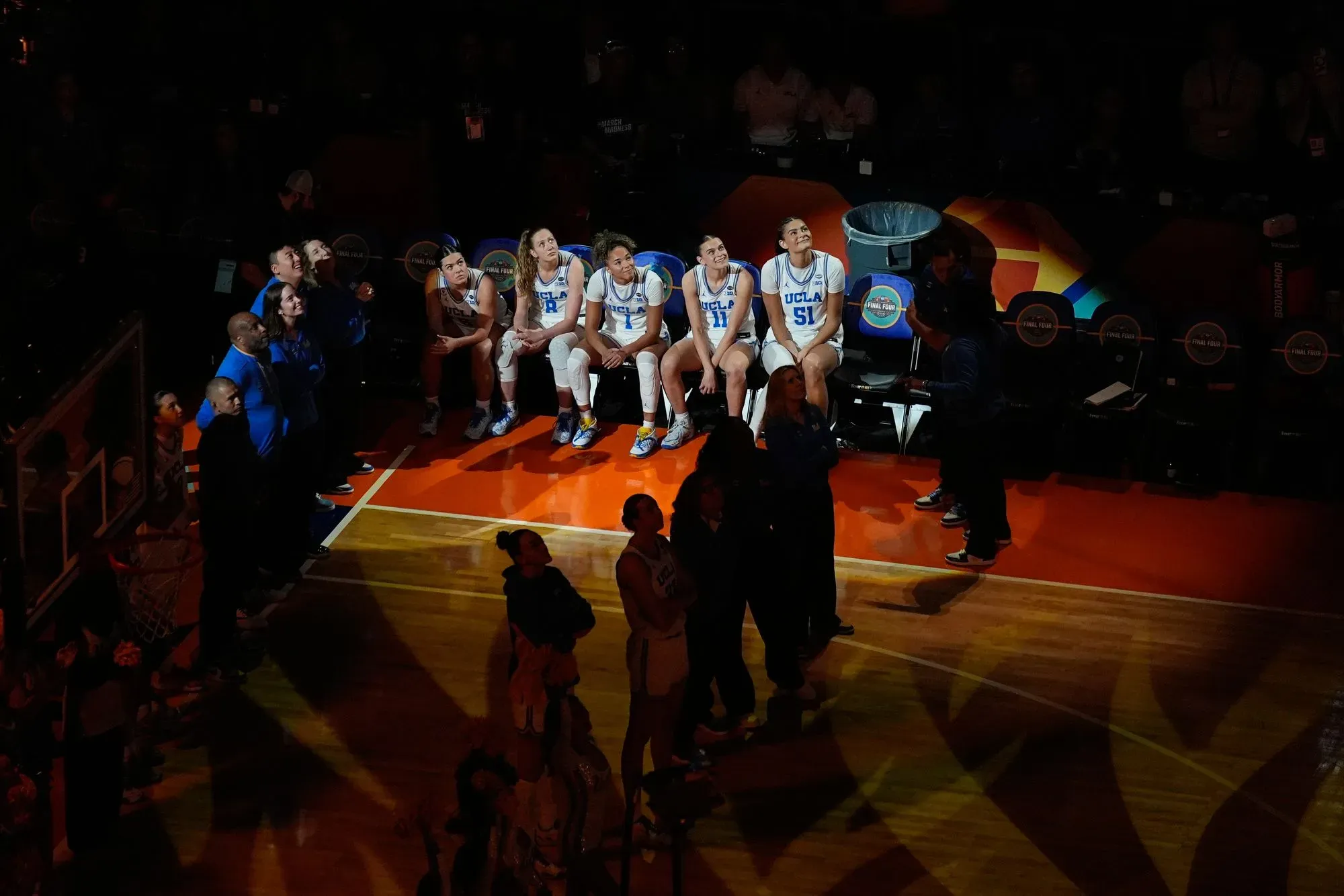 فريق جامعة كاليفورنيا في لوس أنجلوس يجلس على مقاعد البدلاء في أجواء احتفالية بعد فوزهم التاريخي بلقب بطولة كرة السلة للسيدات.