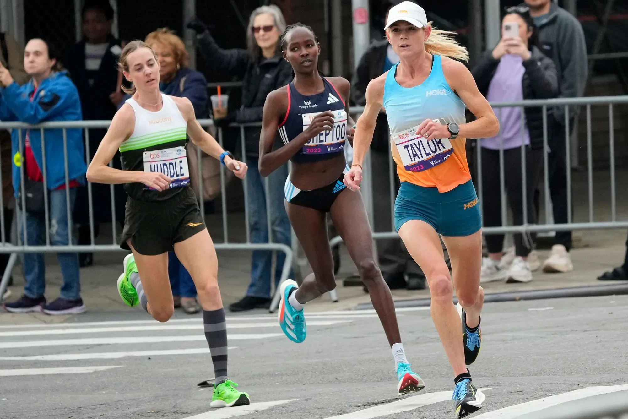 منافسة بين العدائين مولي هودل وكيلين تايلور في ماراثون، حيث تظهر هودل في المقدمة، مما يعكس قوة النساء الرياضيات بعد الحمل.