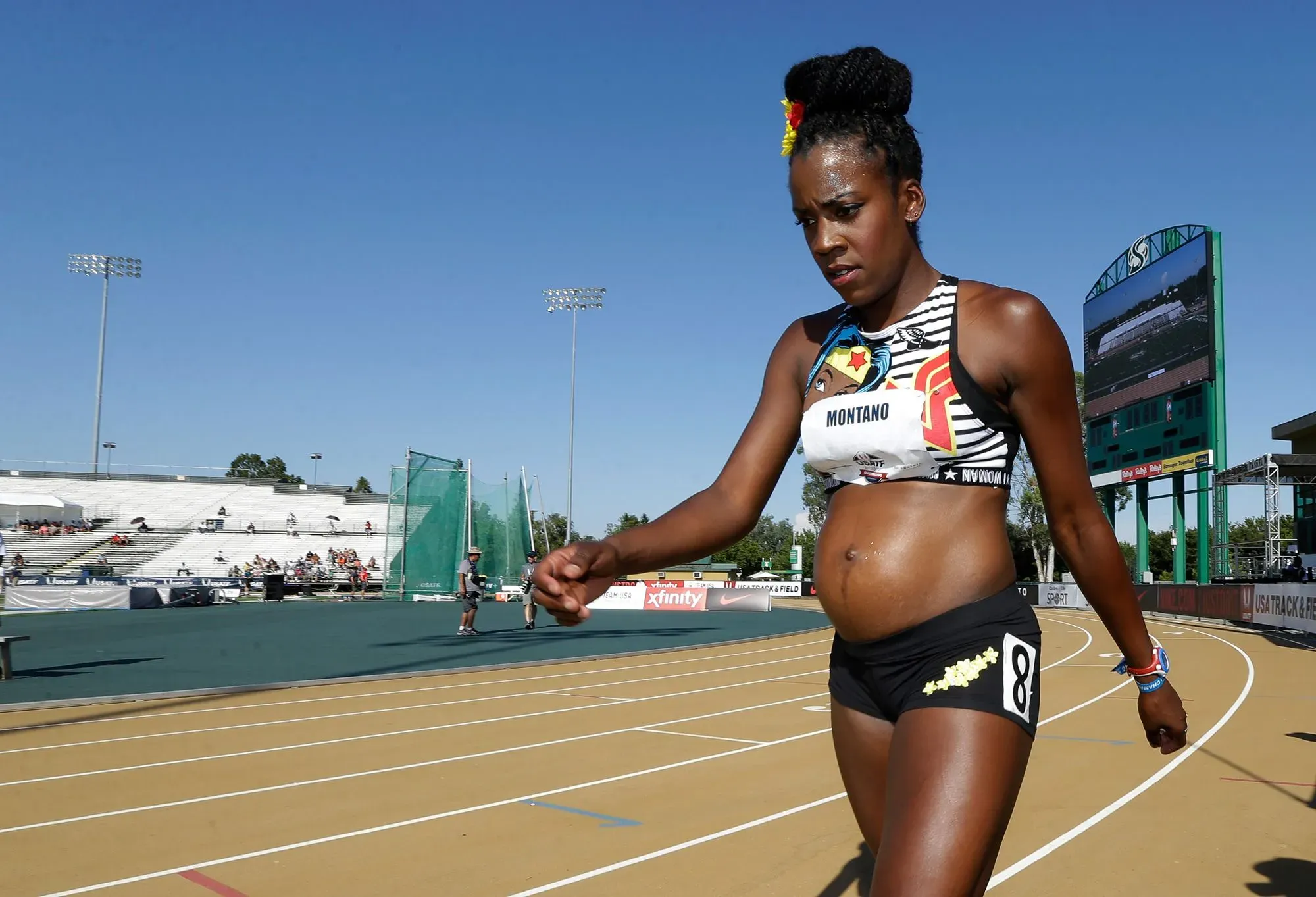 عداءة حامل تتدرب في مضمار رياضي، تظهر عزمها على تحدي المعايير التقليدية للحمل من خلال ممارسة الرياضة.