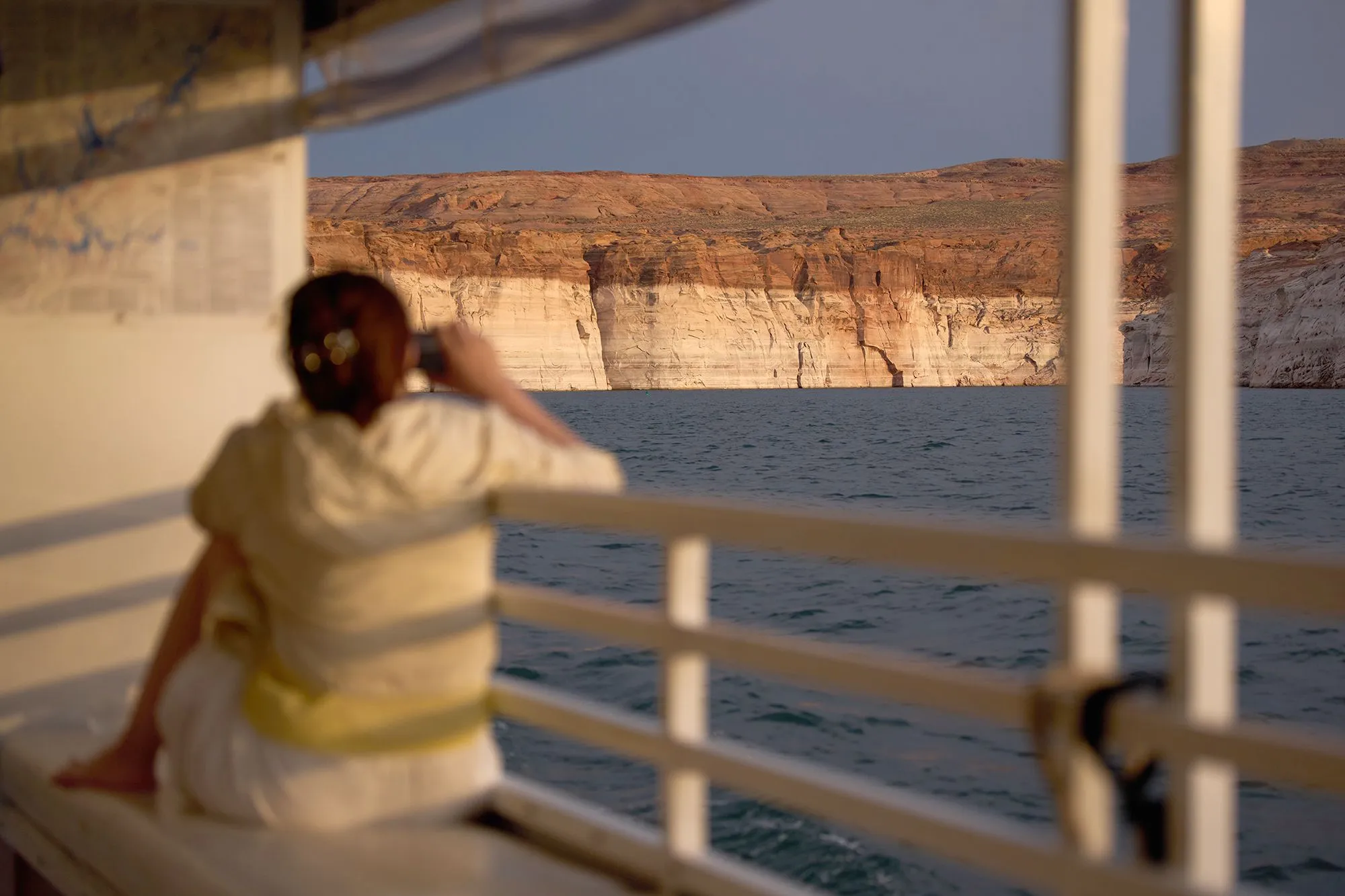 امرأة تجلس على قارب تراقب انخفاض منسوب مياه بحيرة Lake Powell بين المنحدرات الصخرية، مما يعكس أزمة الجفاف في غرب الولايات المتحدة.