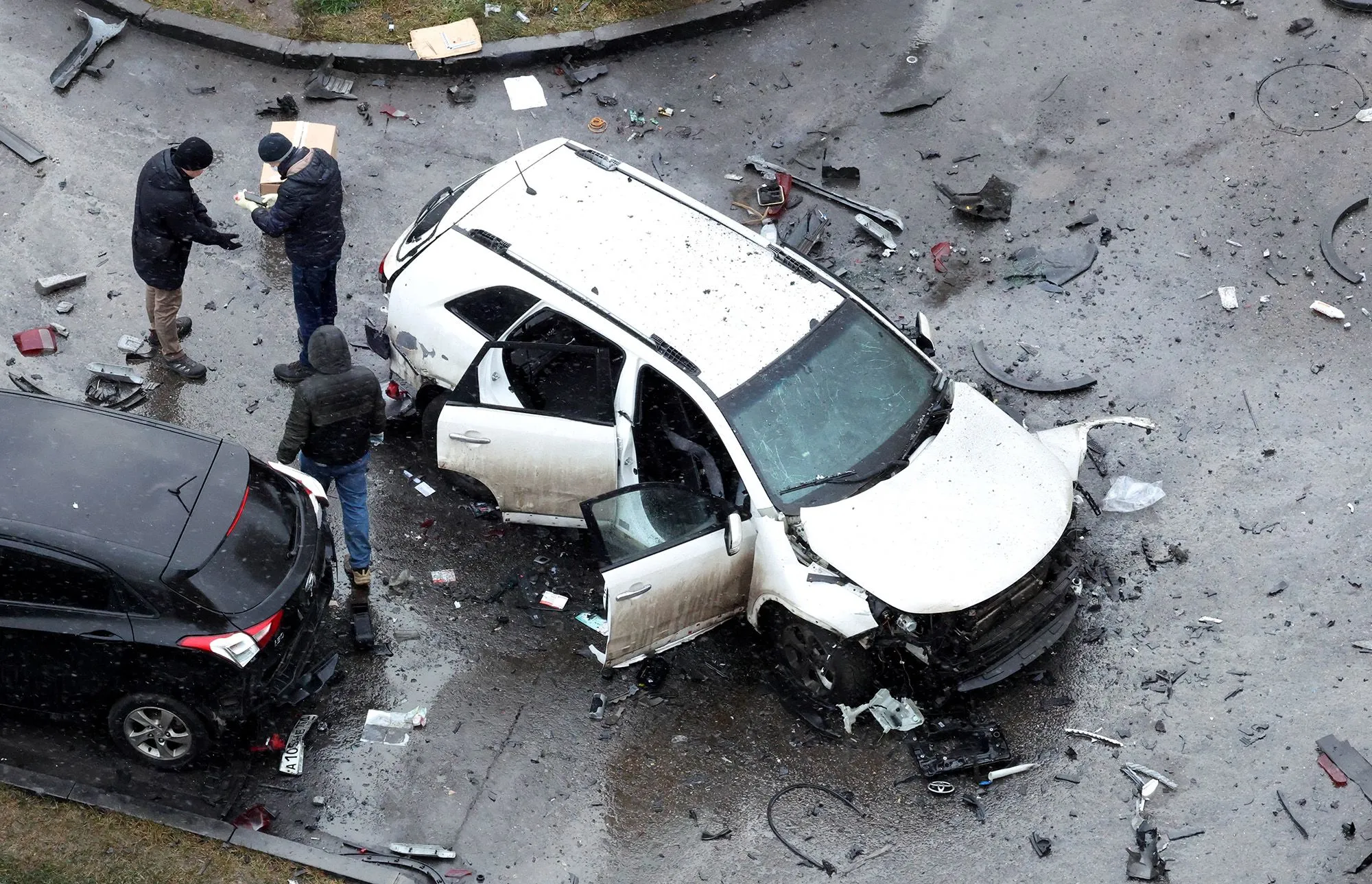 موقع حادث سير في موسكو يظهر سيارة بيضاء متضررة بشدة، مع وجود رجال يتفقدون الأضرار، مما يعكس تصاعد التوترات الأمنية حول الكرملين.