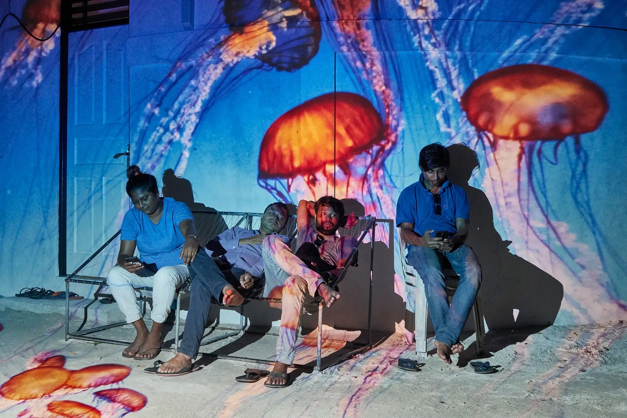 مجموعة من الأشخاص يجلسون على أريكة تحت ضوء مسلّط يظهر قناديل البحر، مما يعكس تأثير التغير المناخي في جزر المالديف.